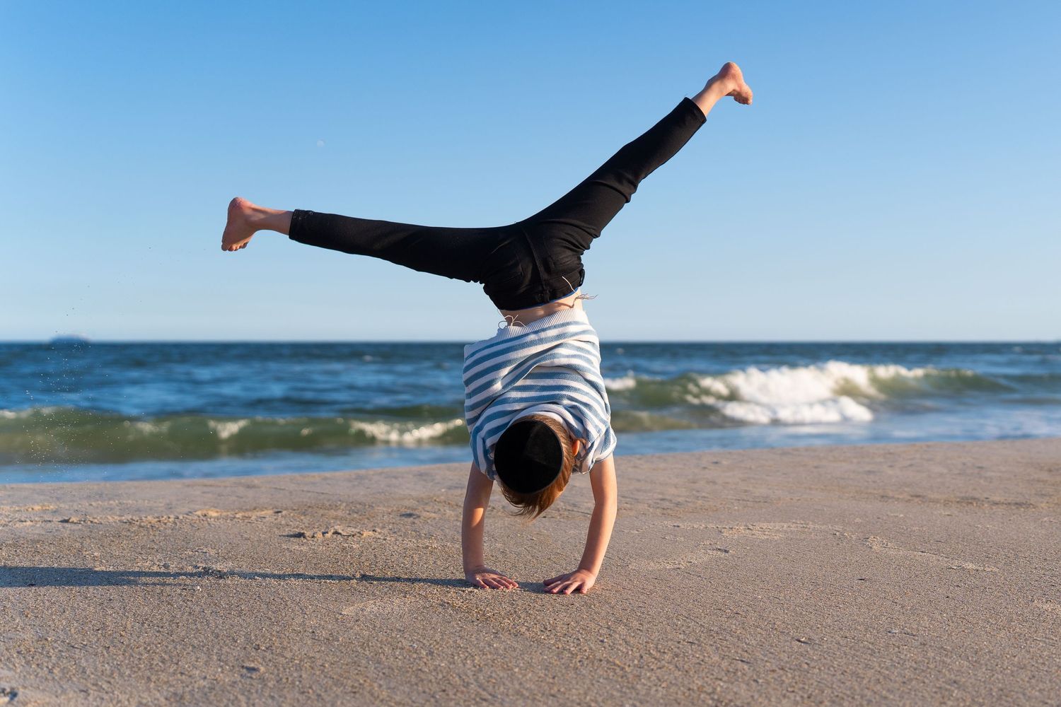 A sequence of photos showing someone performing a cartwheel on a sandy beach with ocean waves in the background.