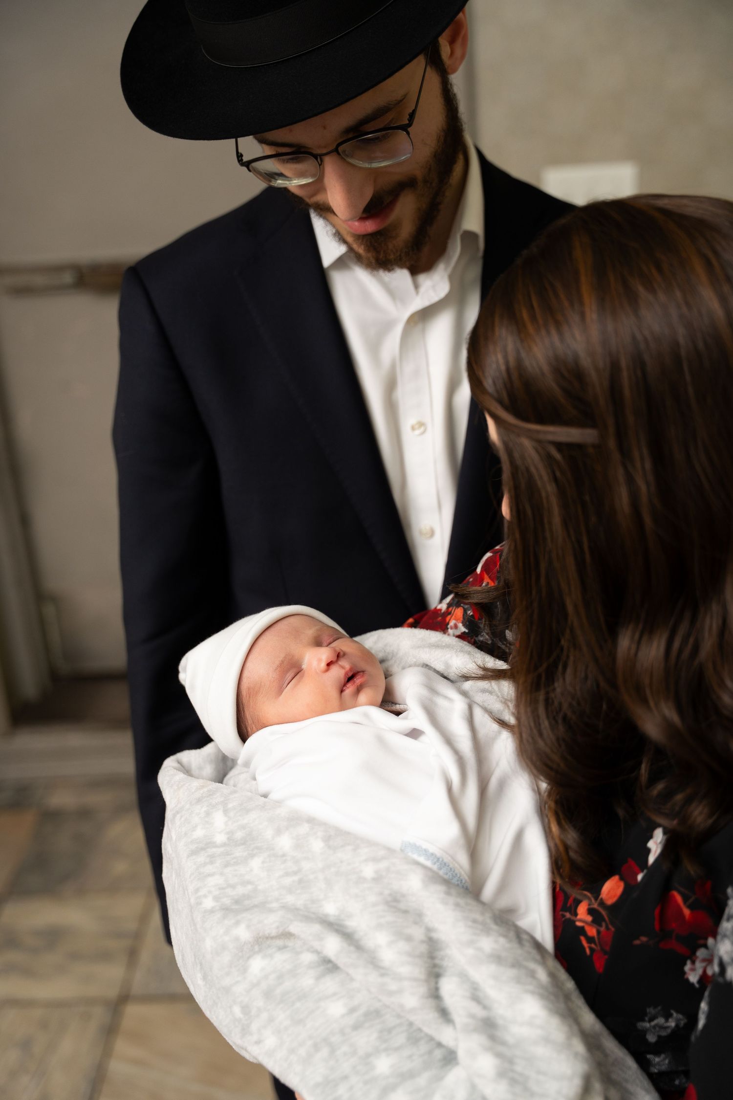 A series of intimate photos showing parents holding their newborn baby wrapped in a white blanket.