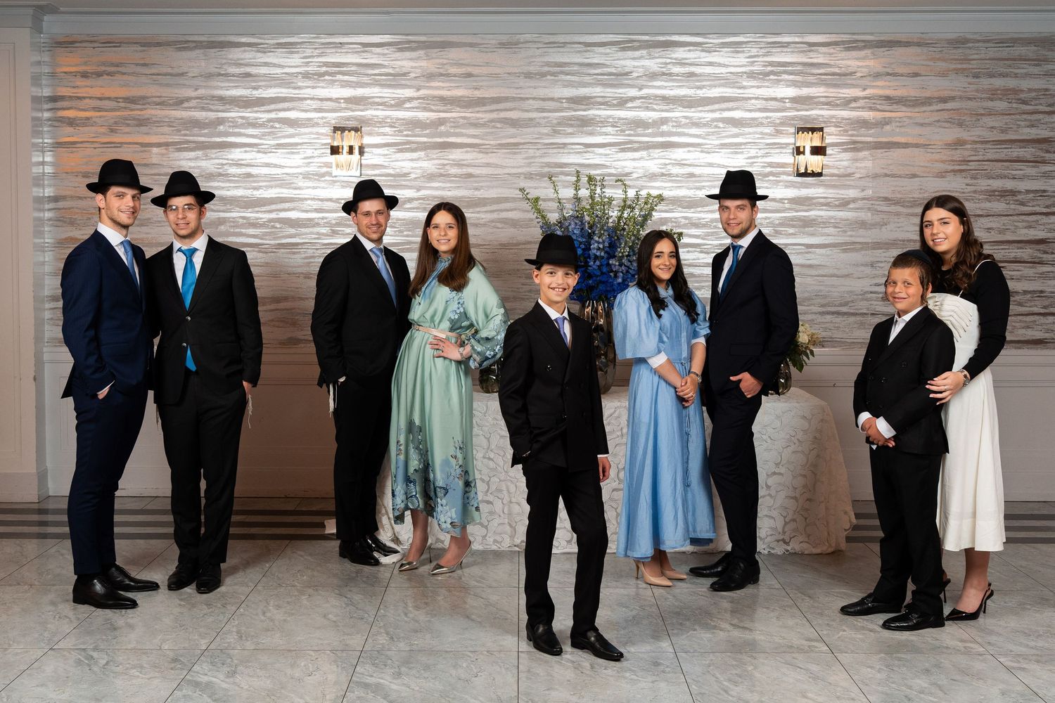 Group of formally dressed young adults posing together in an elegant venue for a special occasion.
