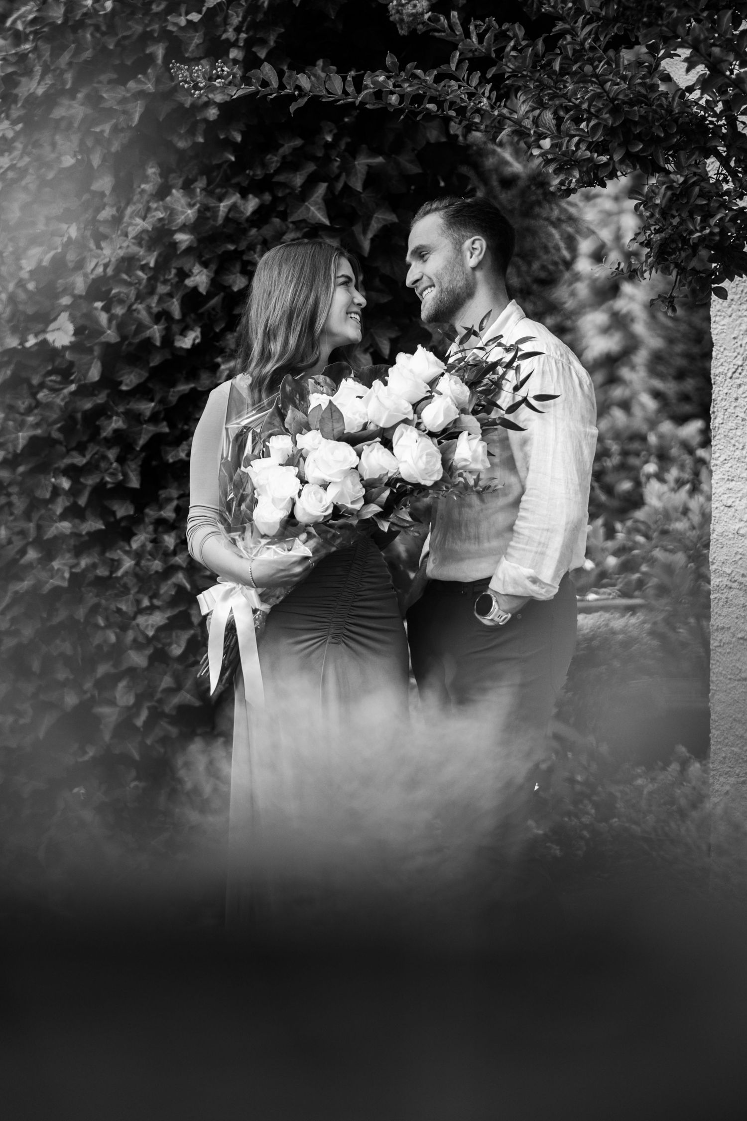 Intimate moment captured in black and white with white roses in the foreground.
