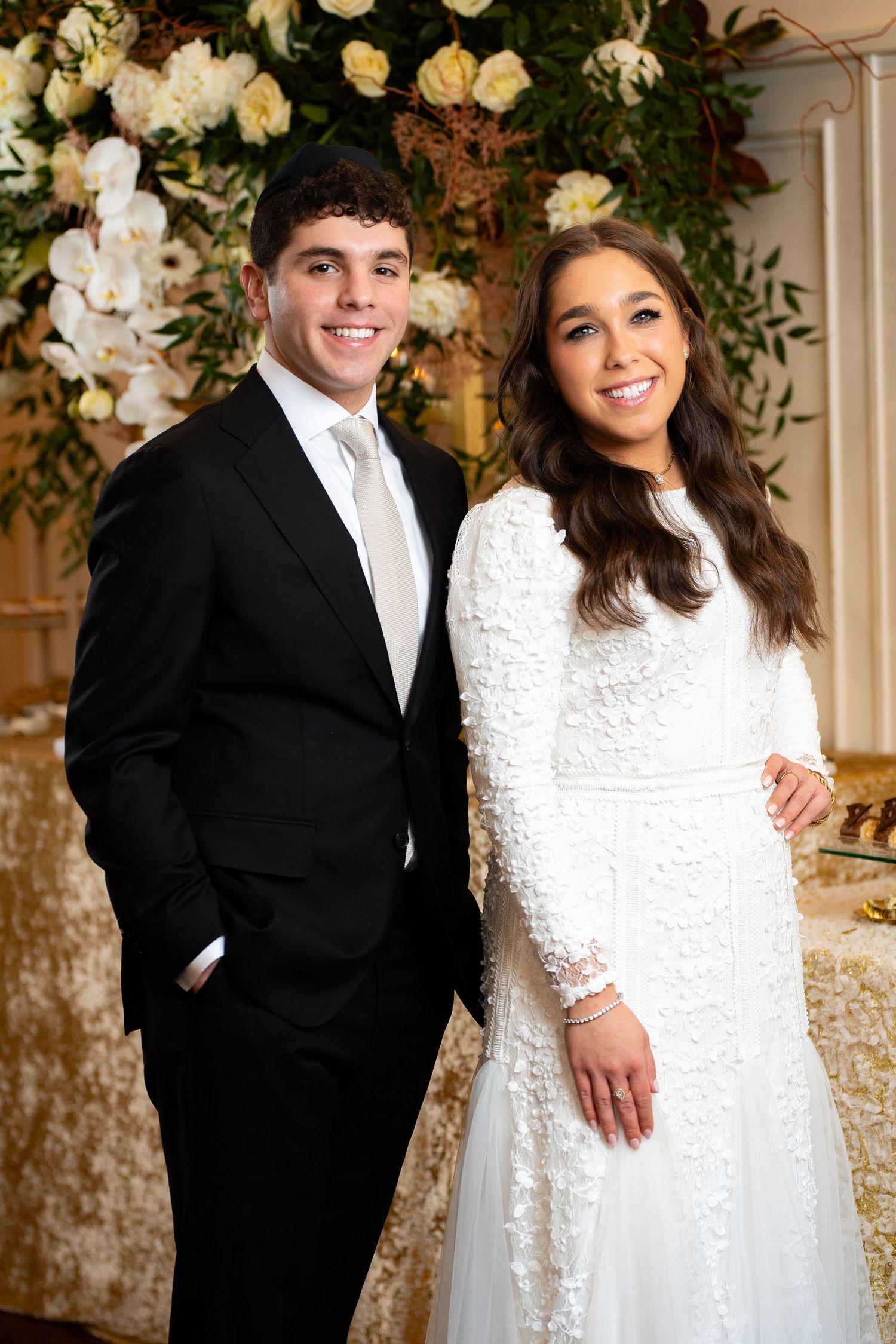 Formal portrait session against floral backdrop with elegant white lace dress.