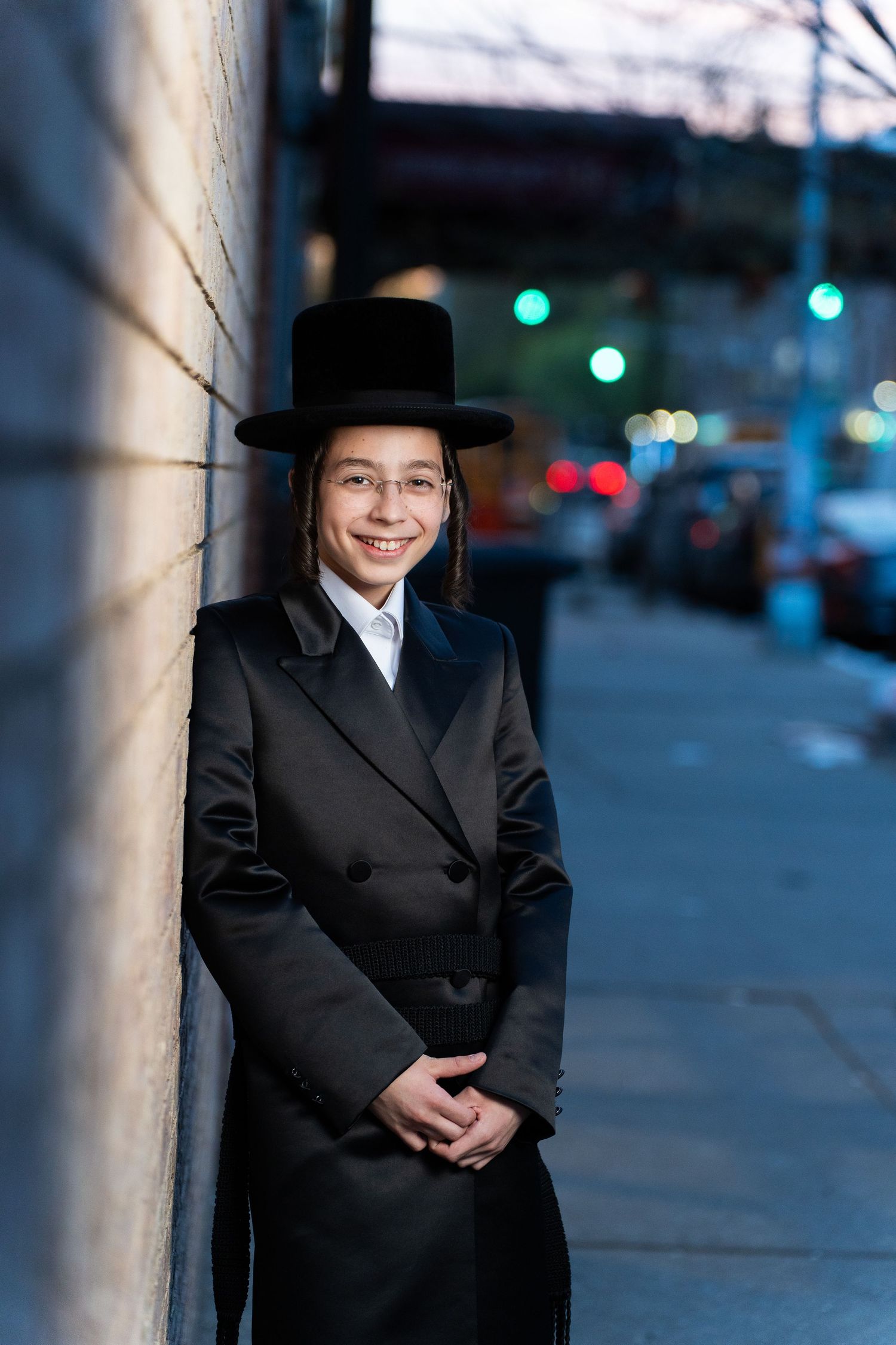 Traditional formal attire captured in evening street photography with city lights.