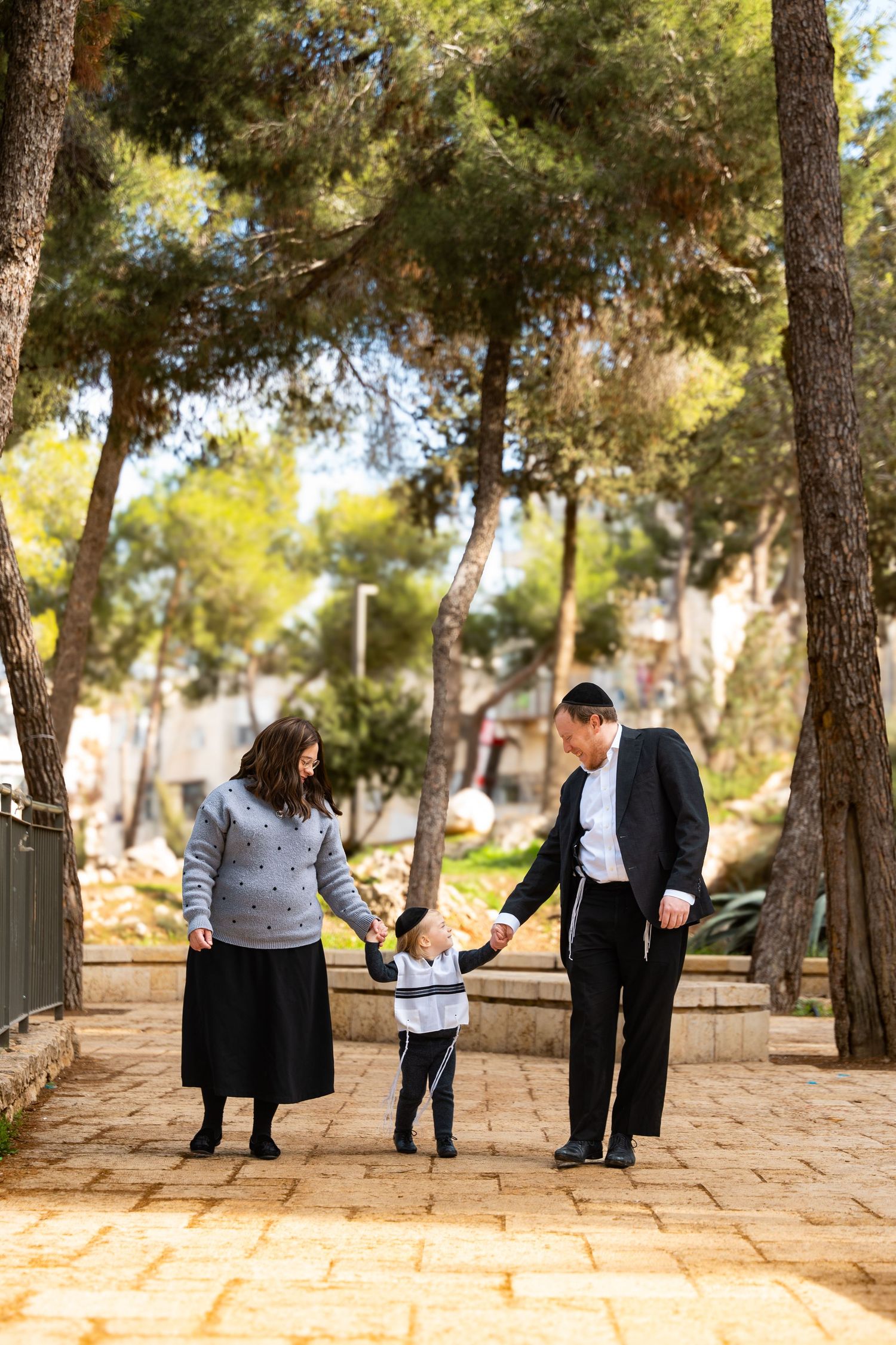 A sequence of candid moments between people walking and interacting in a sunlit park with pine trees.