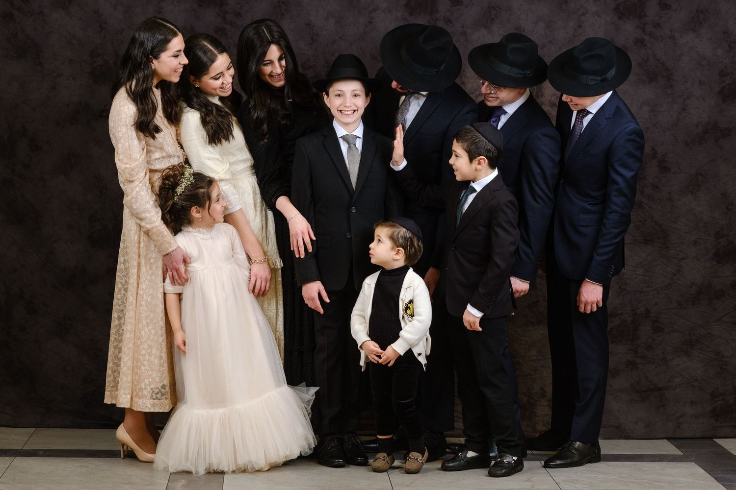 A group portrait against a dark background featuring formal attire and traditional dress.