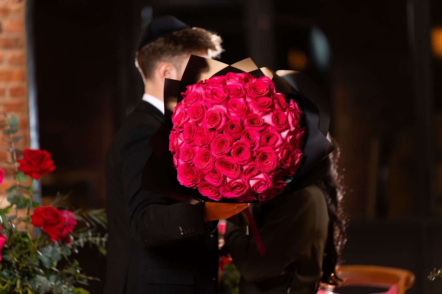 A dramatic backlit scene with a stunning bouquet of red roses.
