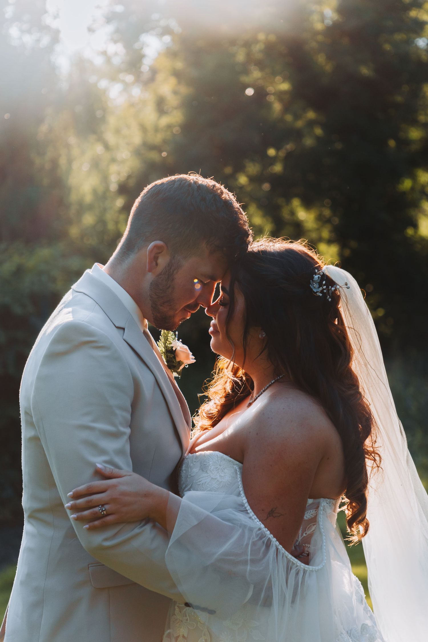 A romantic wedding couple embraces in the golden hour sunlight during their outdoor photoshoot.