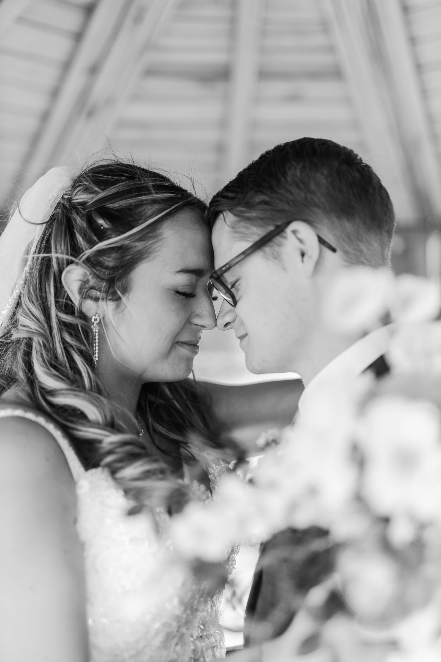 Black and white close-up shots of a couple sharing tender kisses through delicate white flowers.