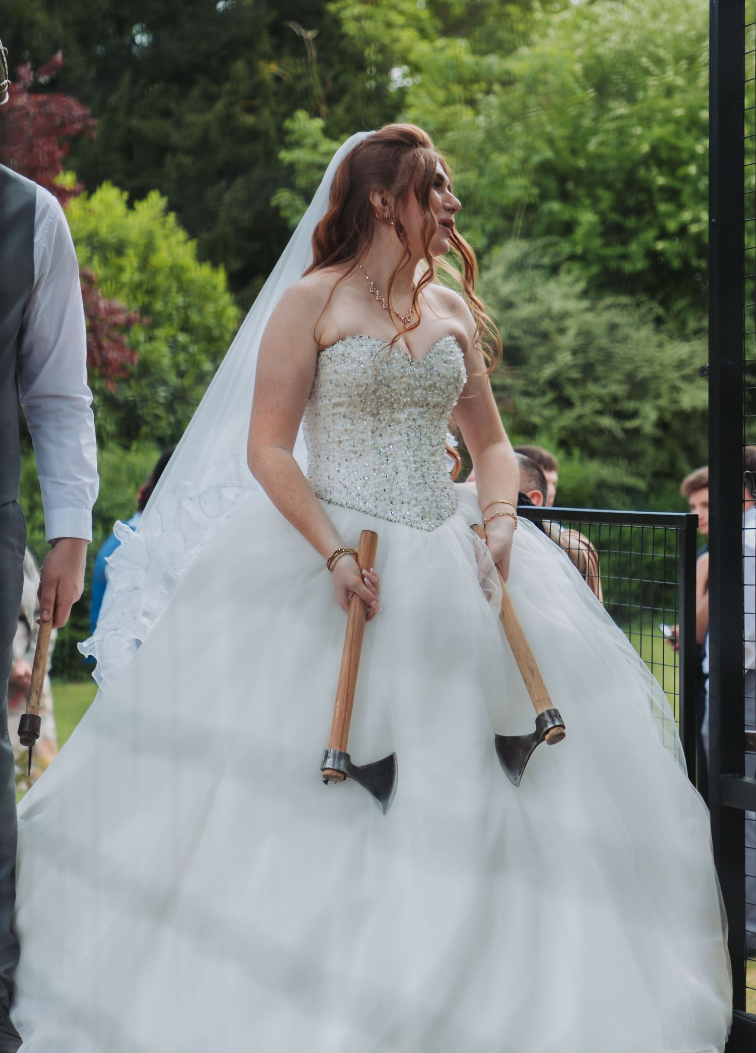 A flowing white wedding dress swirls elegantly against a lush green garden backdrop.
