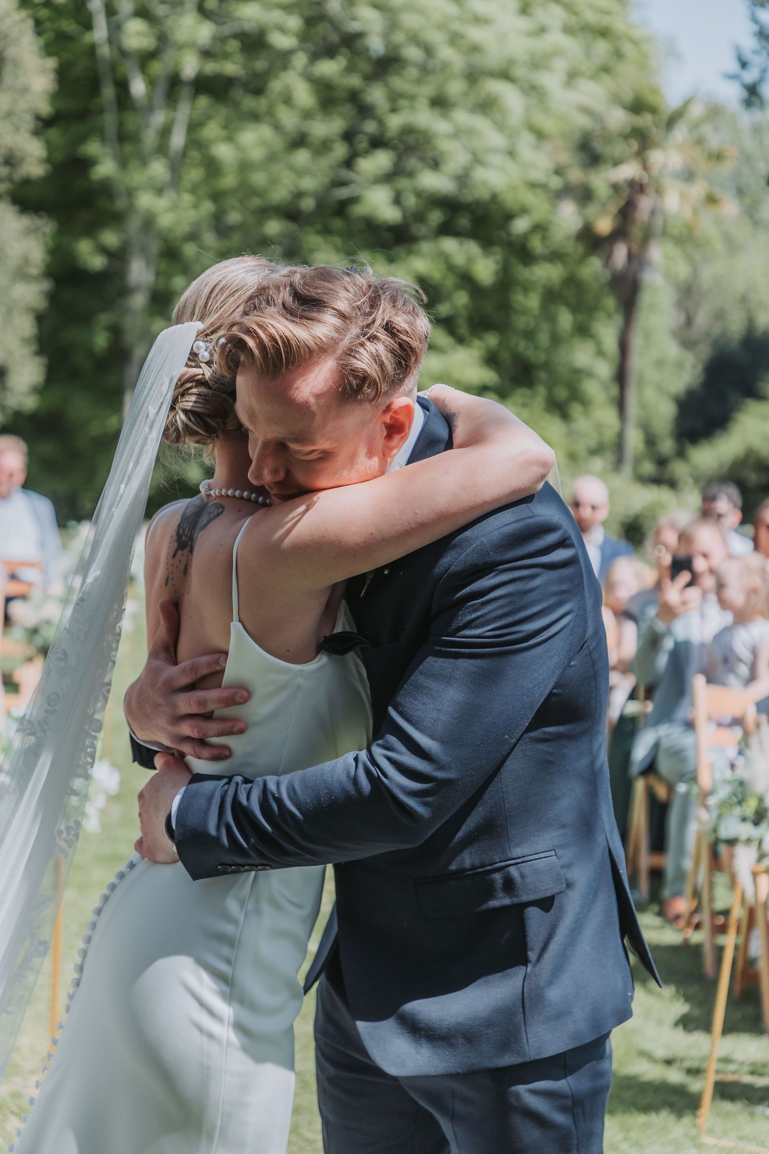 A tender embrace between newlyweds during an outdoor garden wedding celebration.