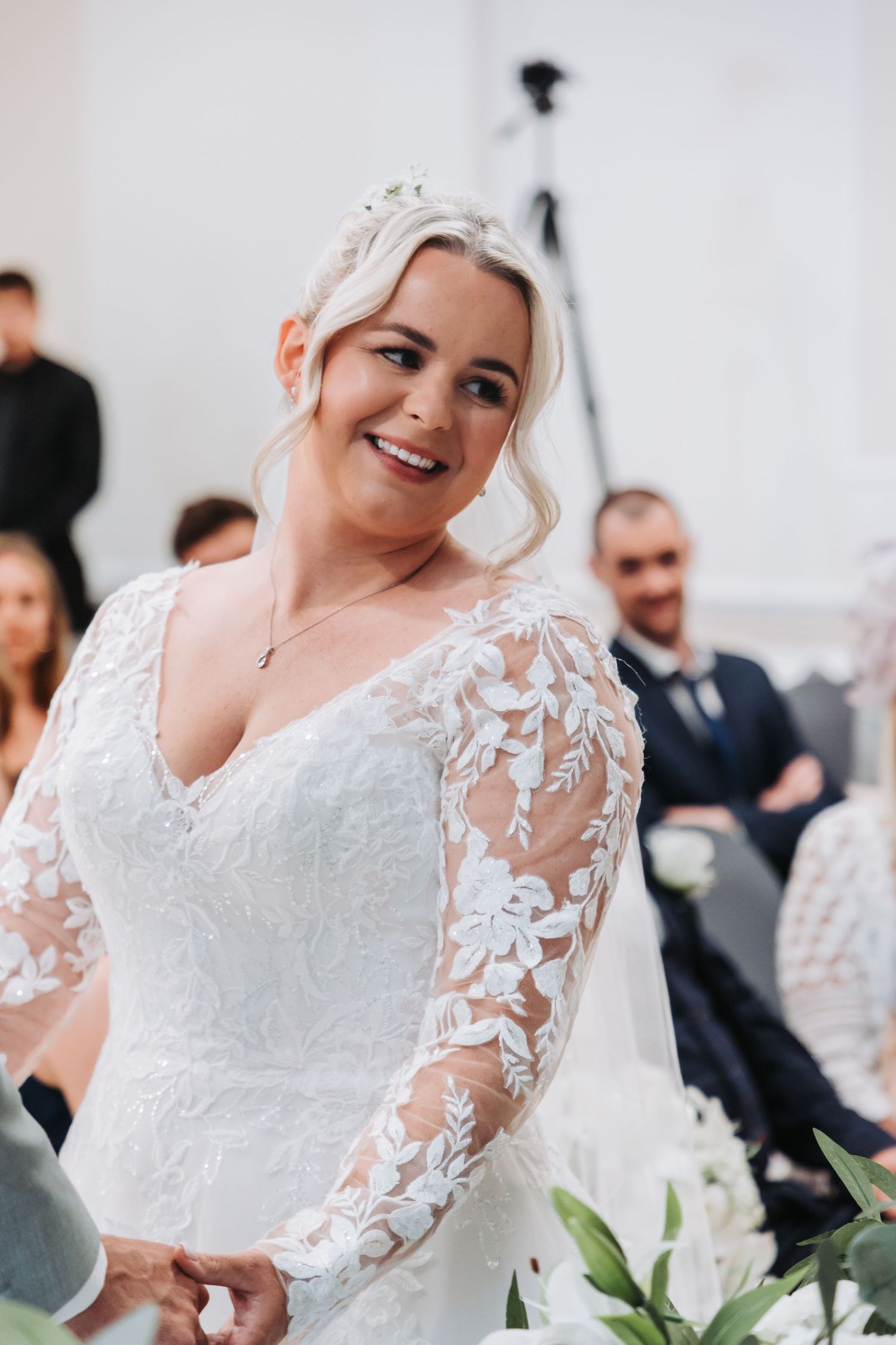 Close-up details of a white lace wedding gown with delicate floral appliques and sheer long sleeves.