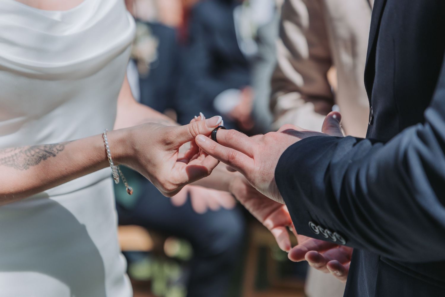 Close-up shot of hands exchanging wedding rings during an intimate ceremony moment.