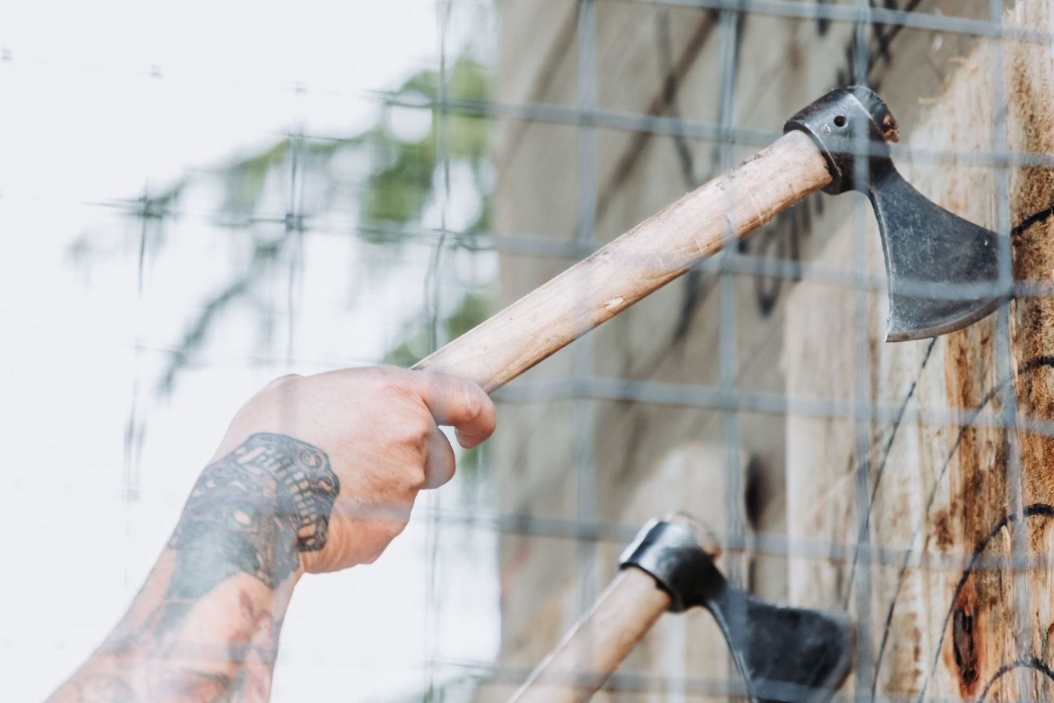 Close-up of hands holding garden tools against a weathered wooden fence background.