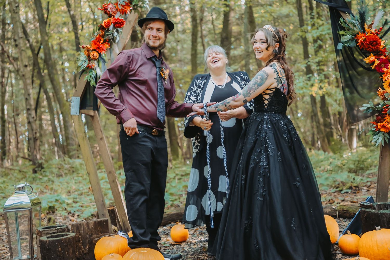 An autumn wedding ceremony with pumpkins and fall decorations in a forest setting.