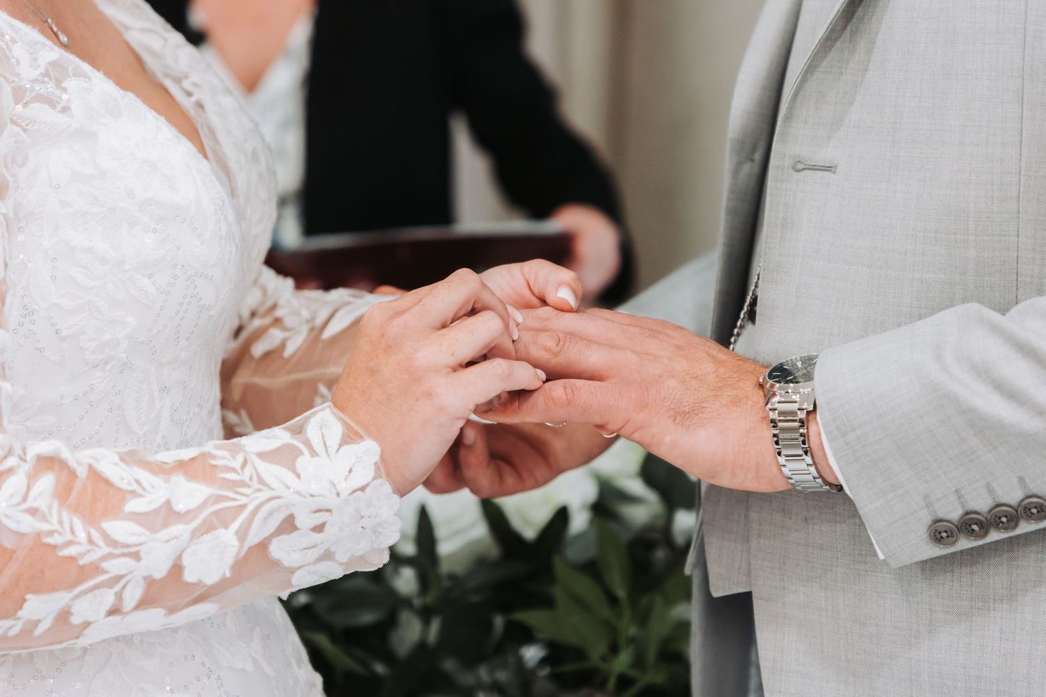 Tender moment captured during a wedding ring exchange ceremony in a bright indoor setting.