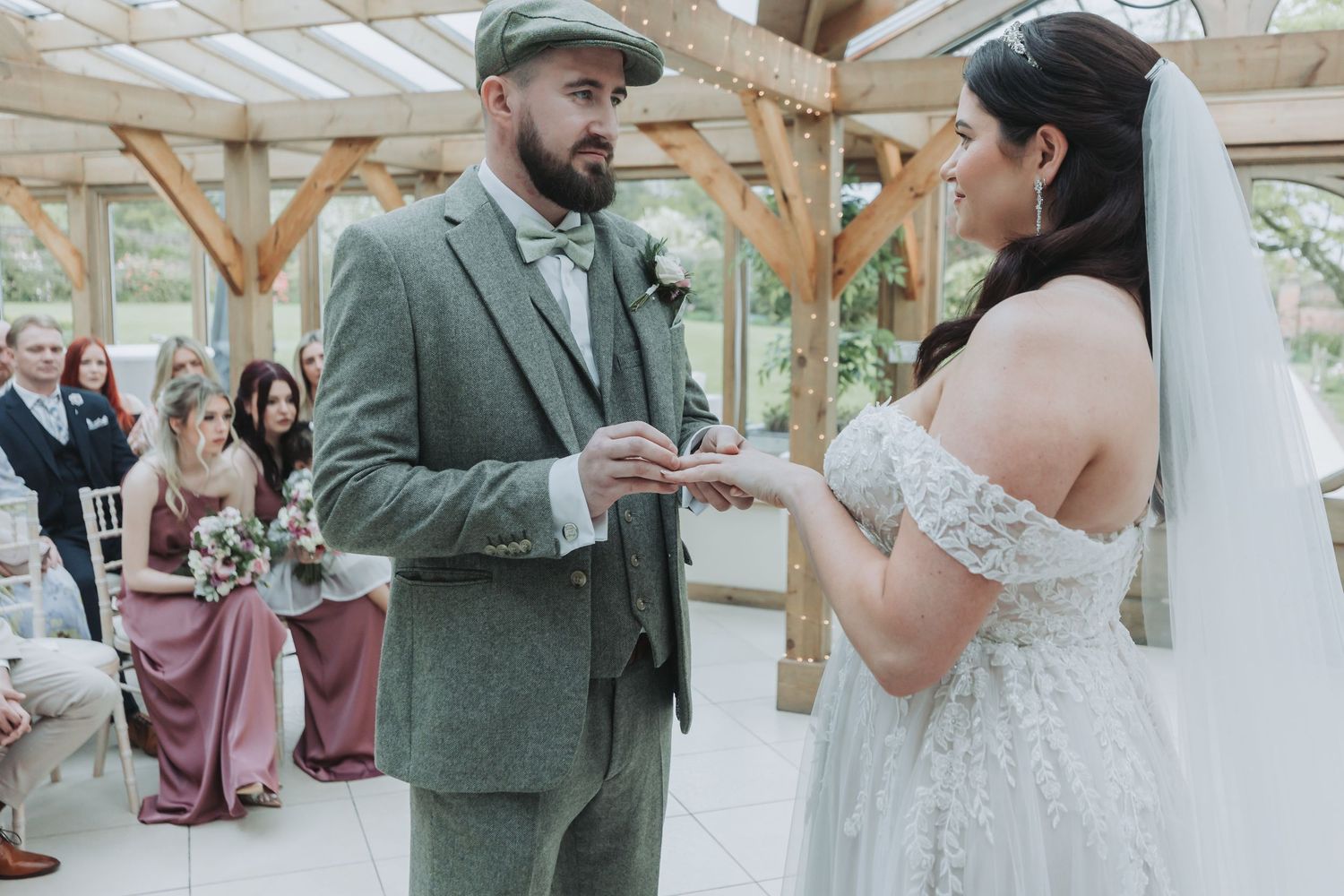 Newlyweds dancing together in an elegant indoor venue decorated with pink and white floral arrangements.