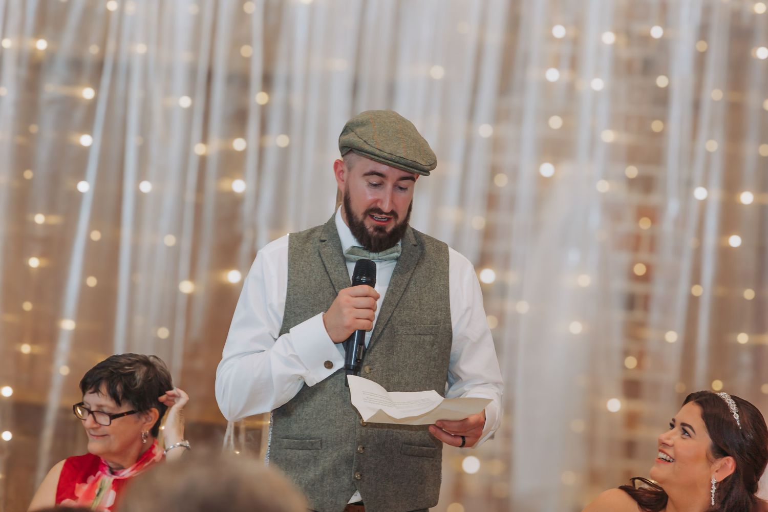 People celebrate at a wedding reception with string lights and decorations in the background.