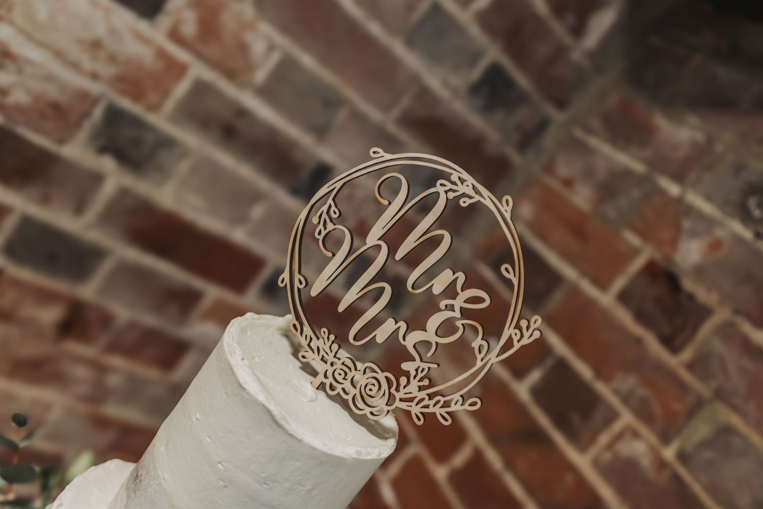 A rustic brick wall backdrop with decorative circular signs featuring elegant floral designs and text.