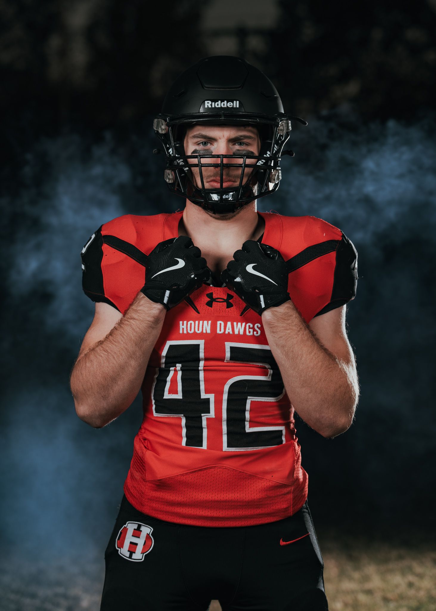 Football player in red jersey number 42 poses with smoke effect.