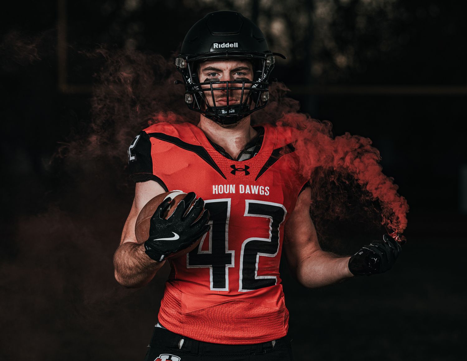Football player in red uniform with smoke effect in dramatic lighting.