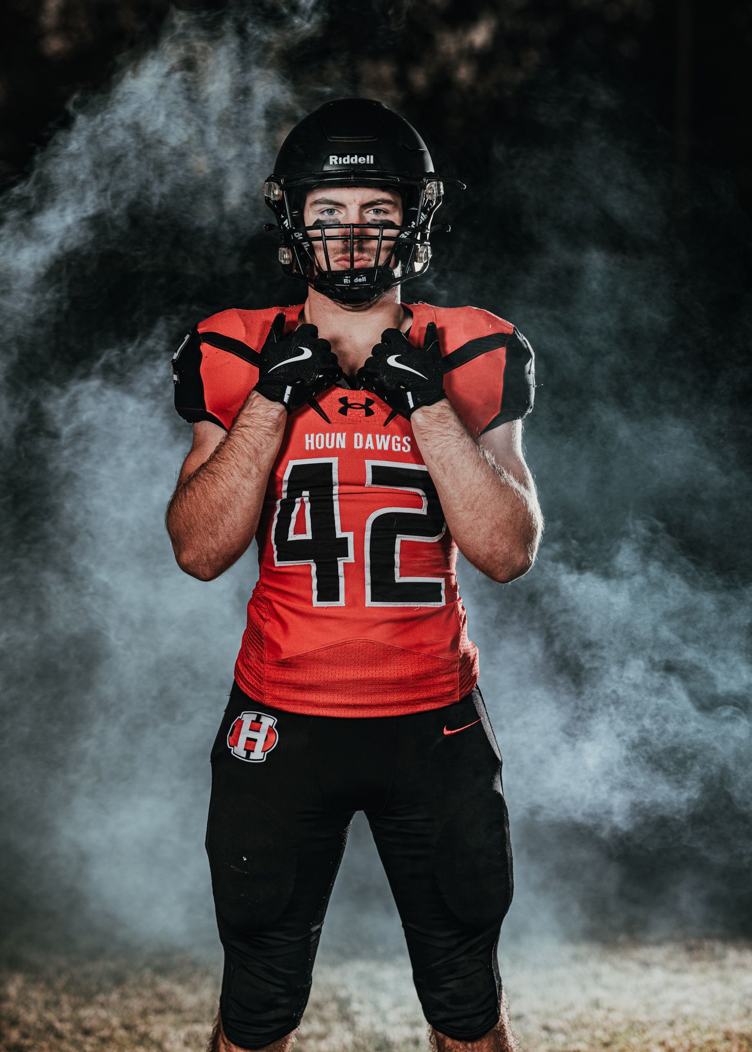 Football player wearing red jersey number 42 poses in dramatic smoke effect lighting.
