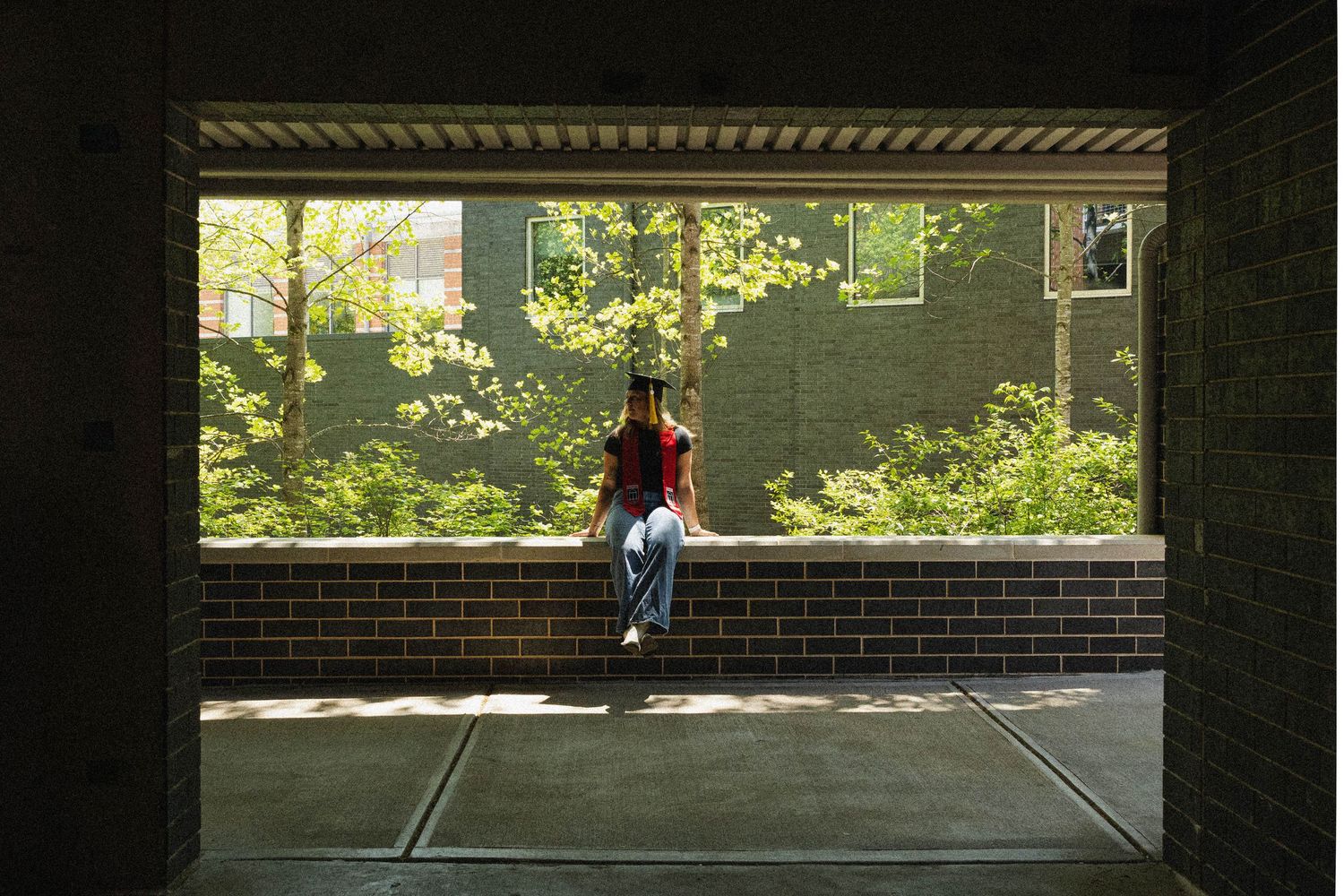 Graduate silhouetted in architectural framed window on campus building.