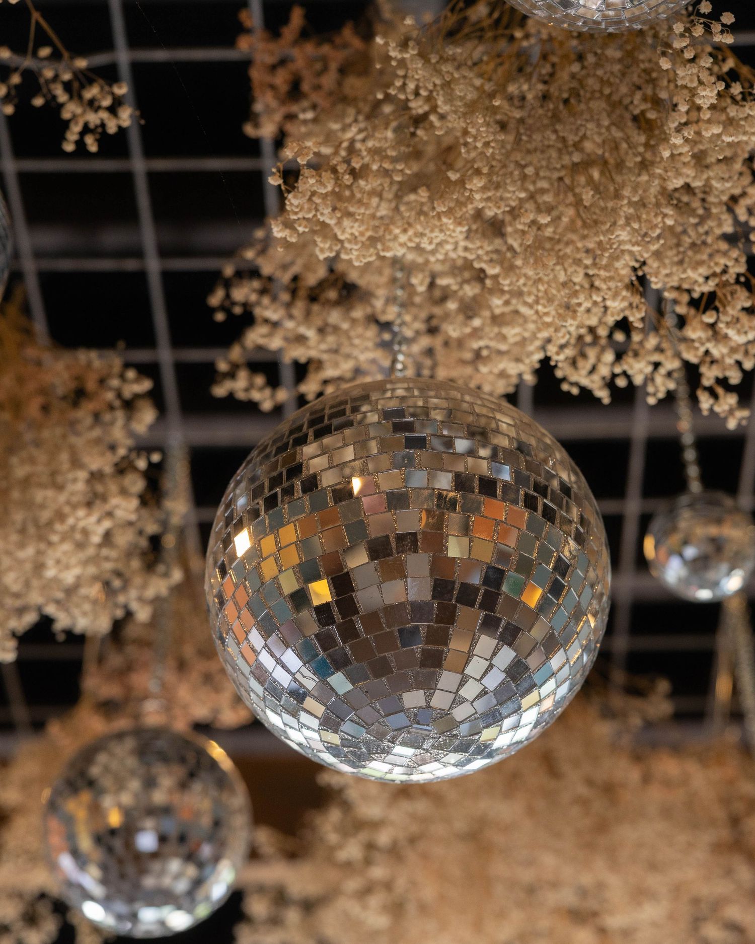 Disco ball and delicate floral decorations create an elegant party atmosphere by hanging from above.