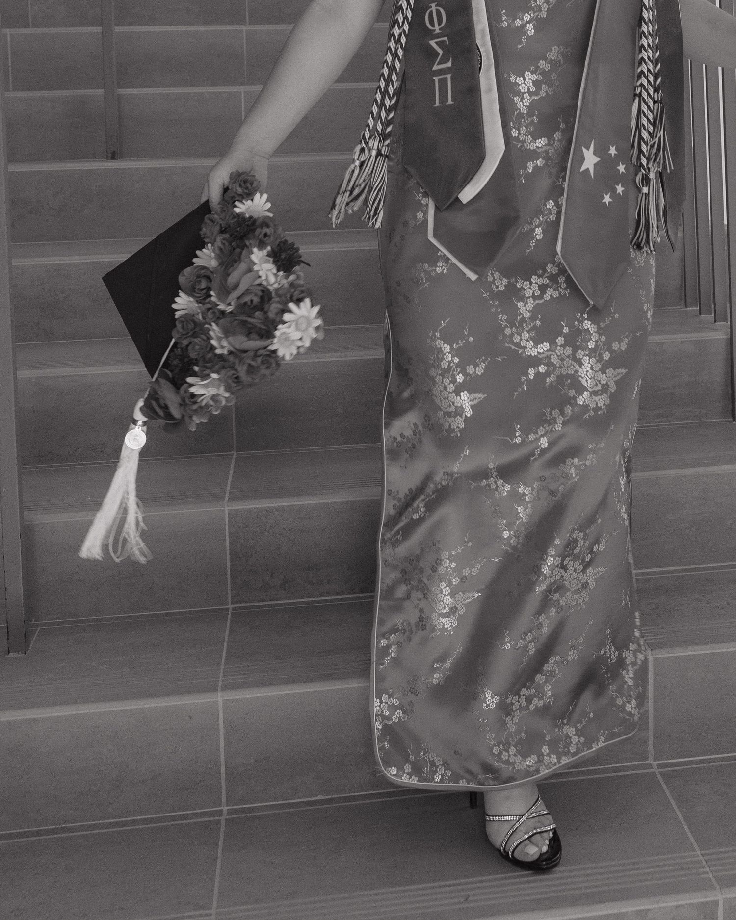 A black and white photo showing a traditional Asian dress with floral patterns and a decorative parasol on tiled steps.