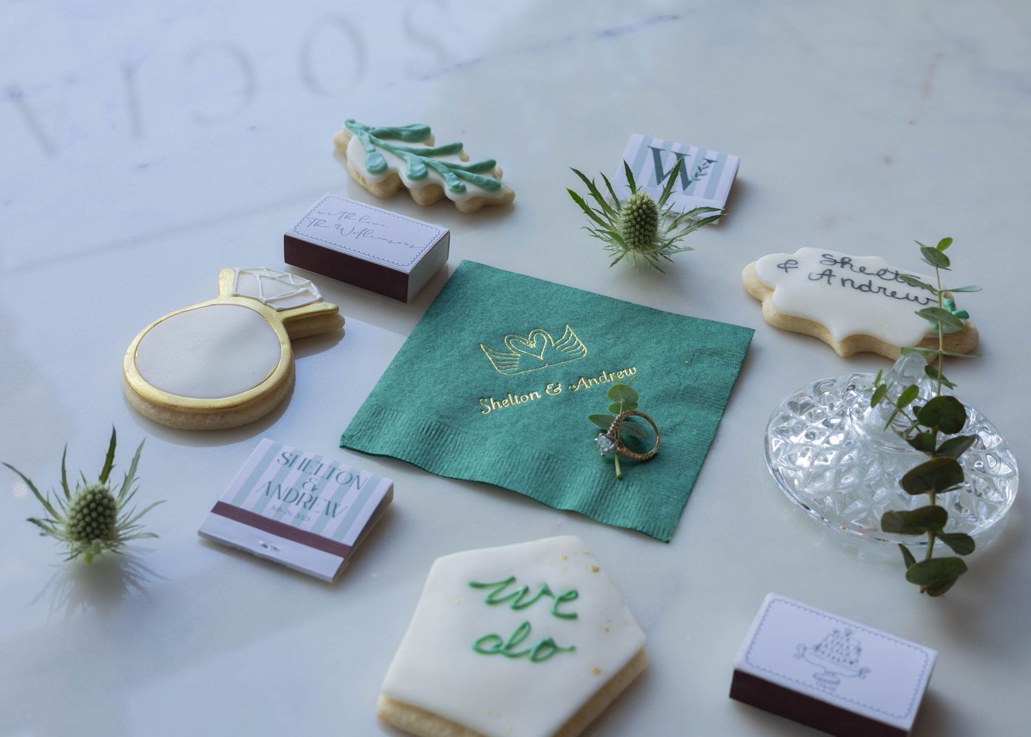 Elegant wedding stationery set in green and white with delicate floral details and calligraphy arranged on a light surface.