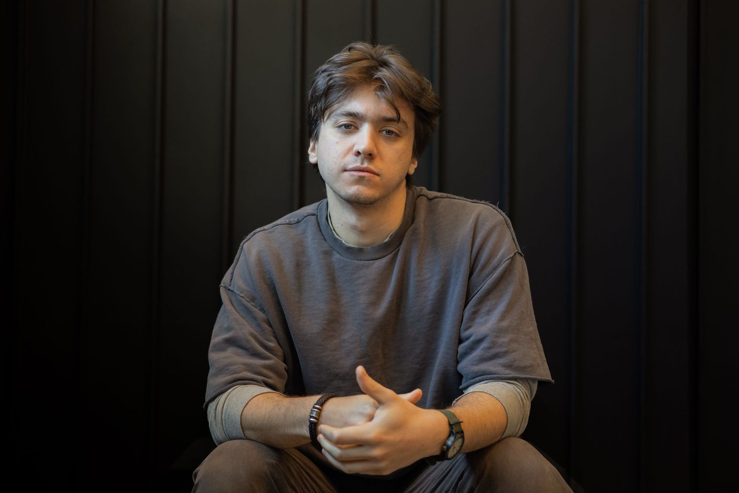 A sequence of casual portraits showing someone in a gray sweatshirt against a dark background.