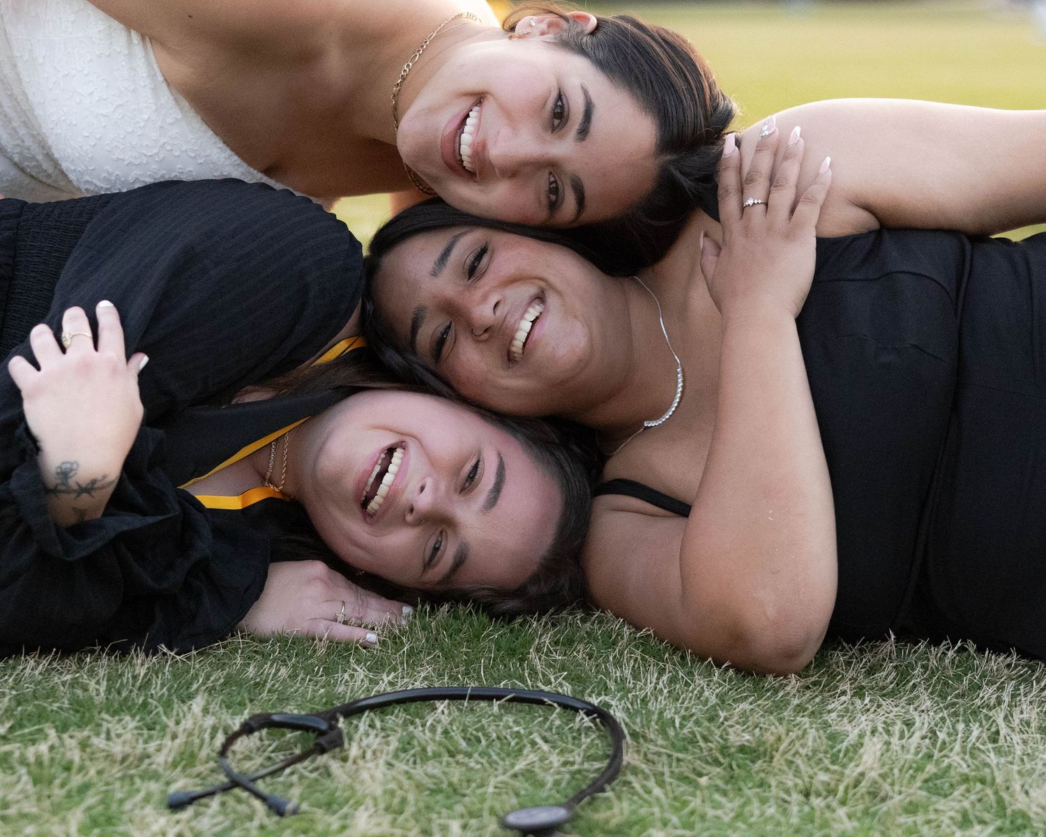 A person lying on grass with long dark hair wearing a black top in a playful outdoor setting.