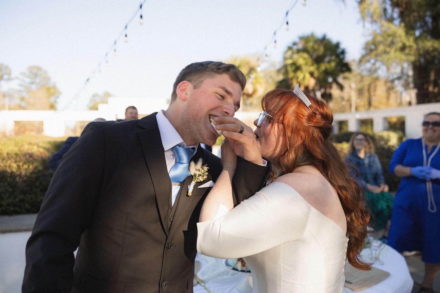 A couple shares a romantic kiss outdoors during a wedding photo session in natural lighting.