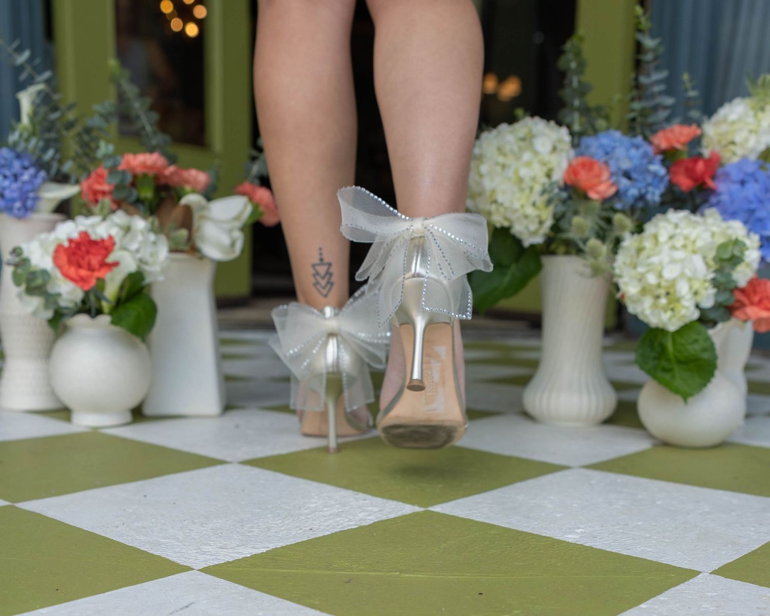A sequence of table settings with floral centerpieces, white vases, and table linens arranged on a green checkered surface.