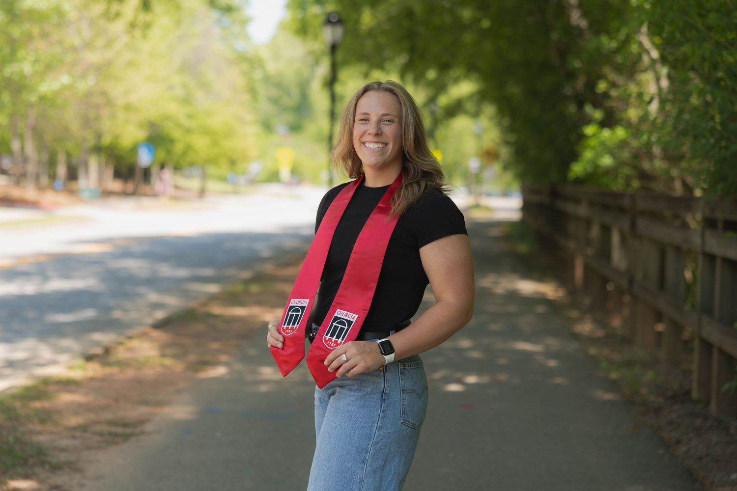 University of Georgia Graduate in casual attire smiling outdoors wearing red academic stoles.