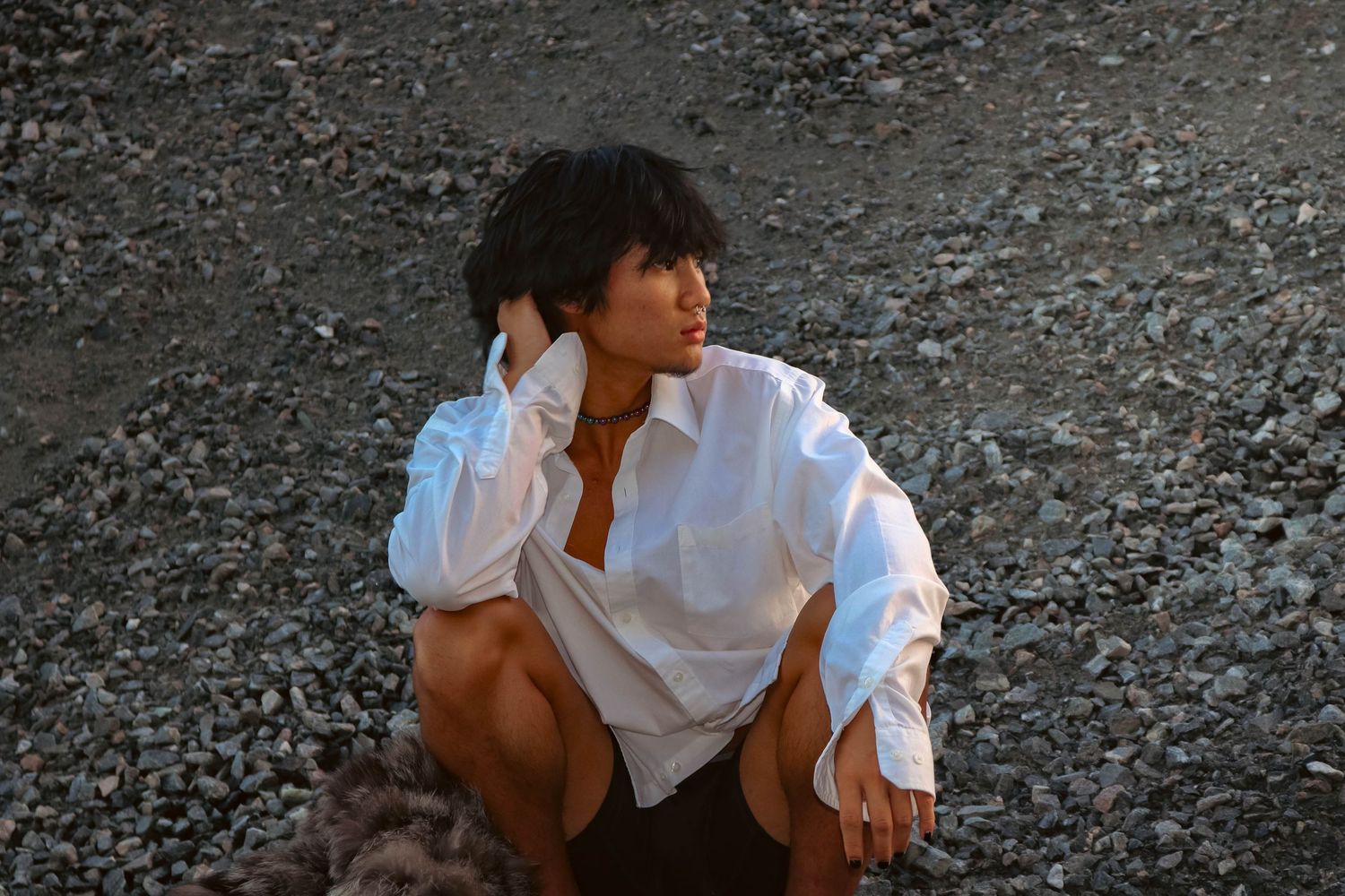 A fashion photo featuring a white button-down shirt against a rocky backdrop.