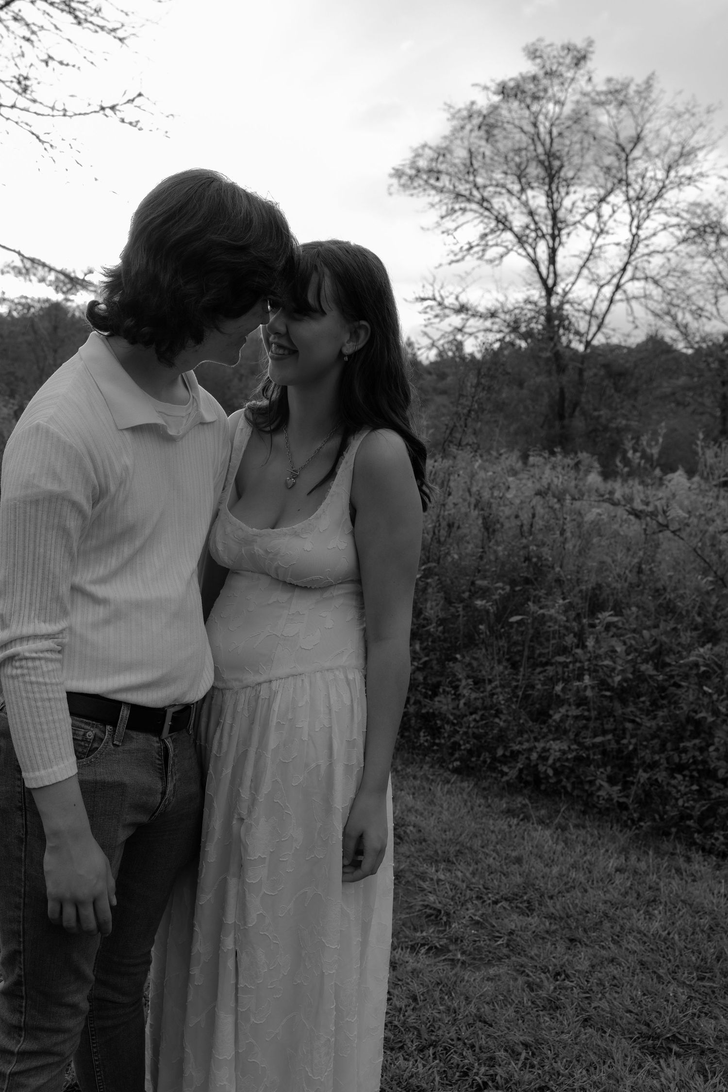 A couple sharing an intimate moment in black and white on a rural path.