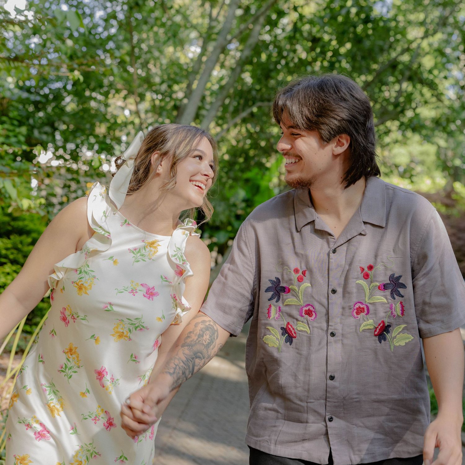 Couple walking together outdoors on a path sharing a joyful moment while wearing floral patterned clothing.
