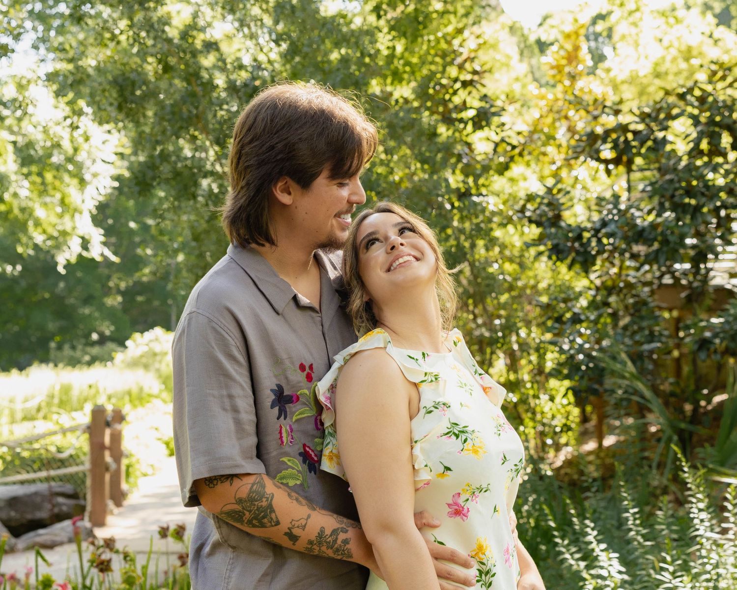 A couple shares romantic moments in a garden setting while surrounded by lush greenery and natural light.