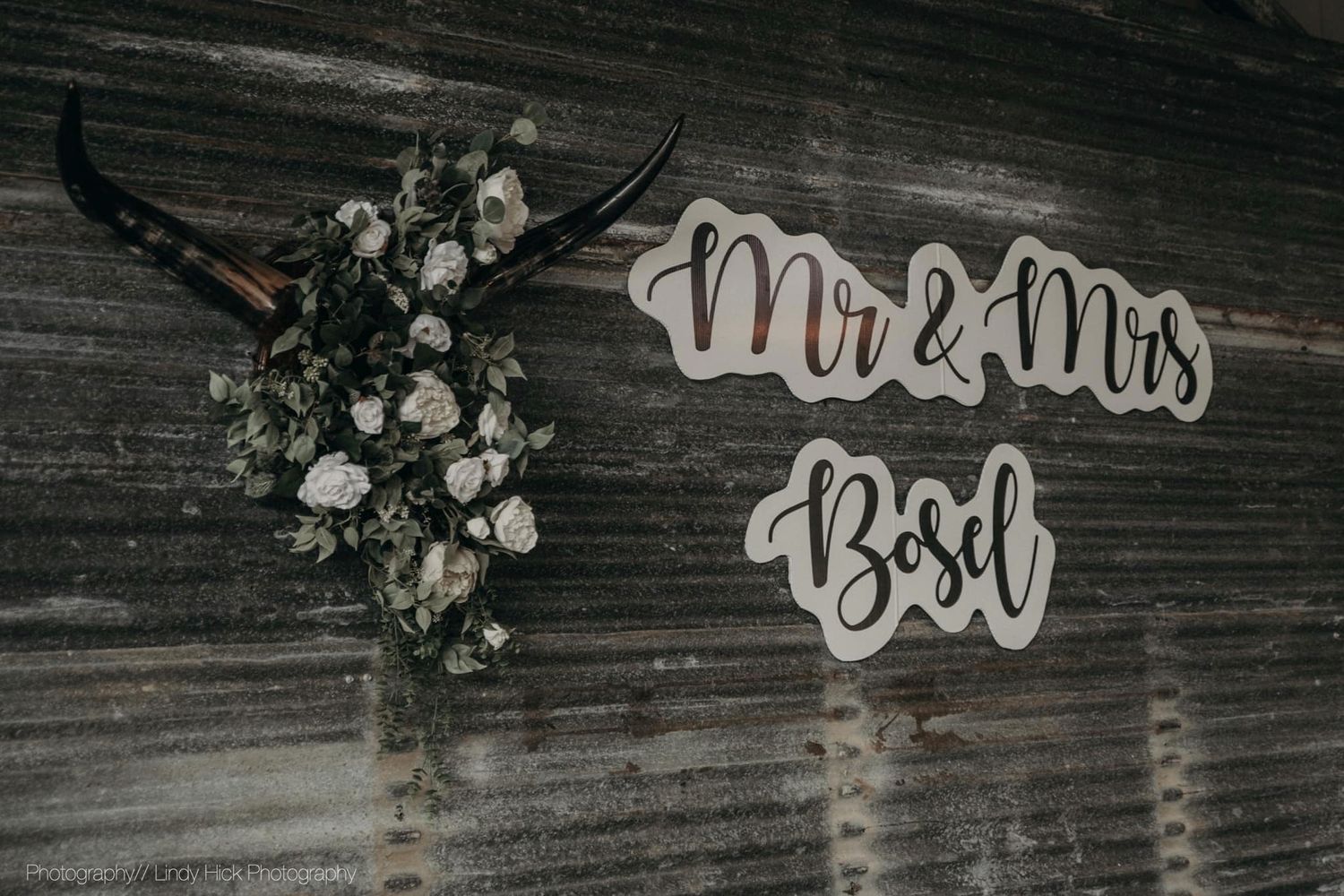 Rustic wooden wall decorated with 'Mr & Mrs' text and floral arrangement.