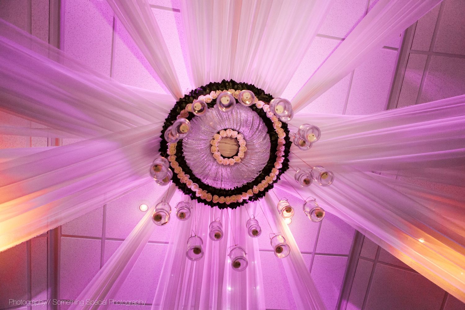 Elegant chandelier with pink and white fabric draping radiating outwards creating a dramatic ceiling display.