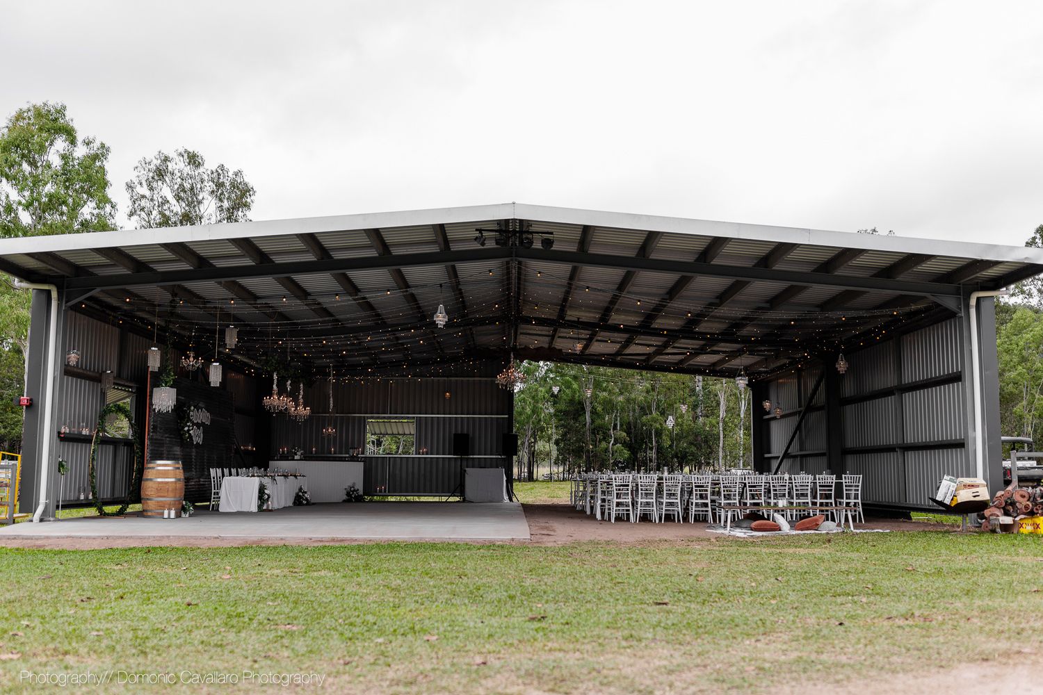 Large open-air metal barn structure set up for an event with chairs and tables visible inside.