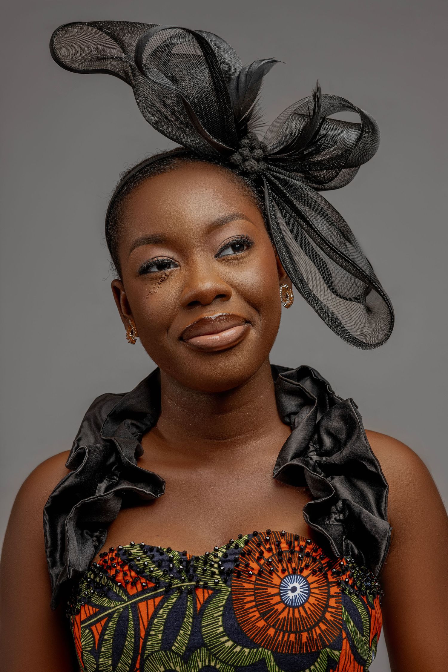 A series of glamour portraits showcasing an elegant dress with vibrant orange and green African print fabric.