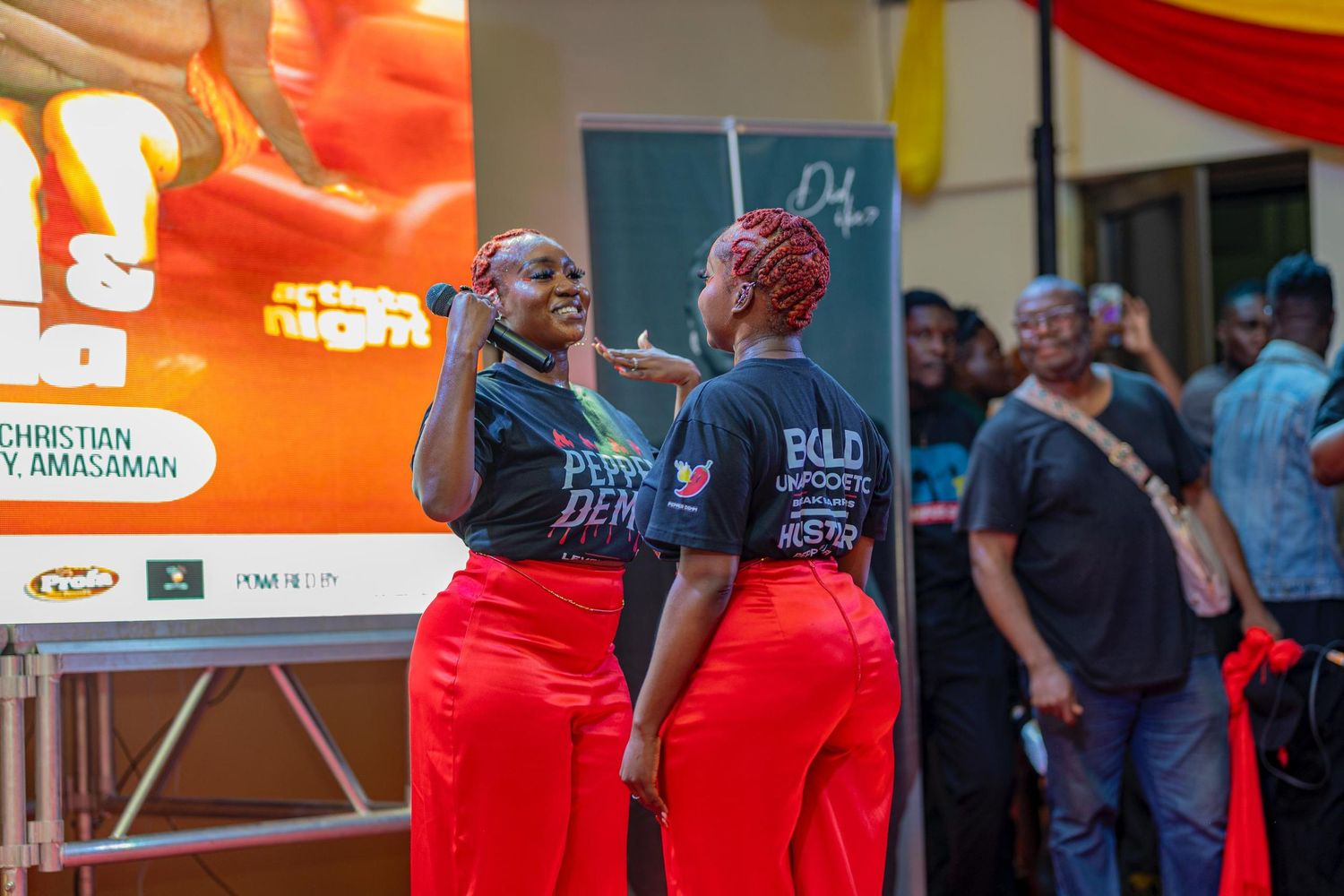 Two staff members in matching red pants and black shirts coordinate at an event.