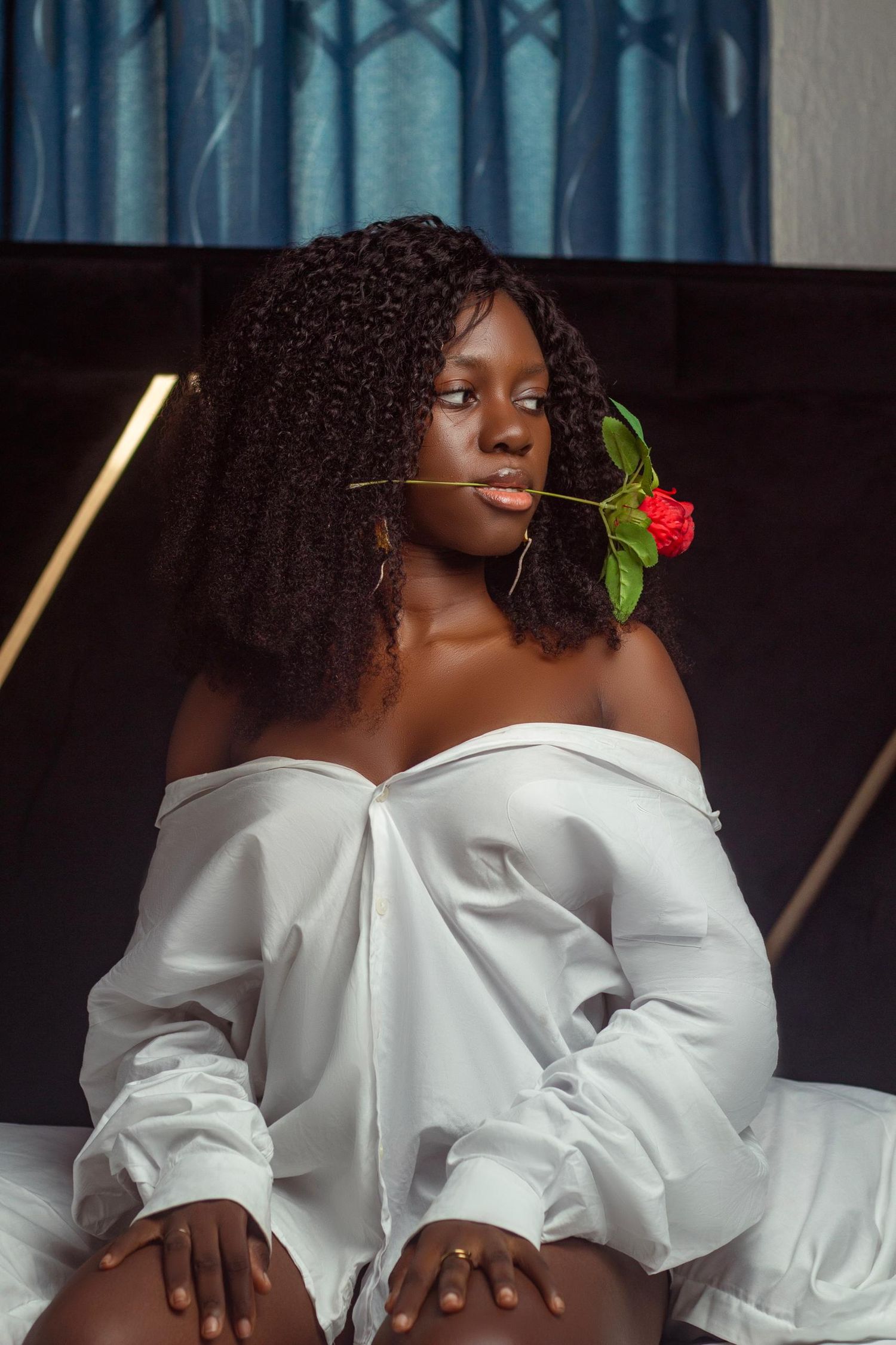 Artistic portrait with model in white shirt holding single red rose.
