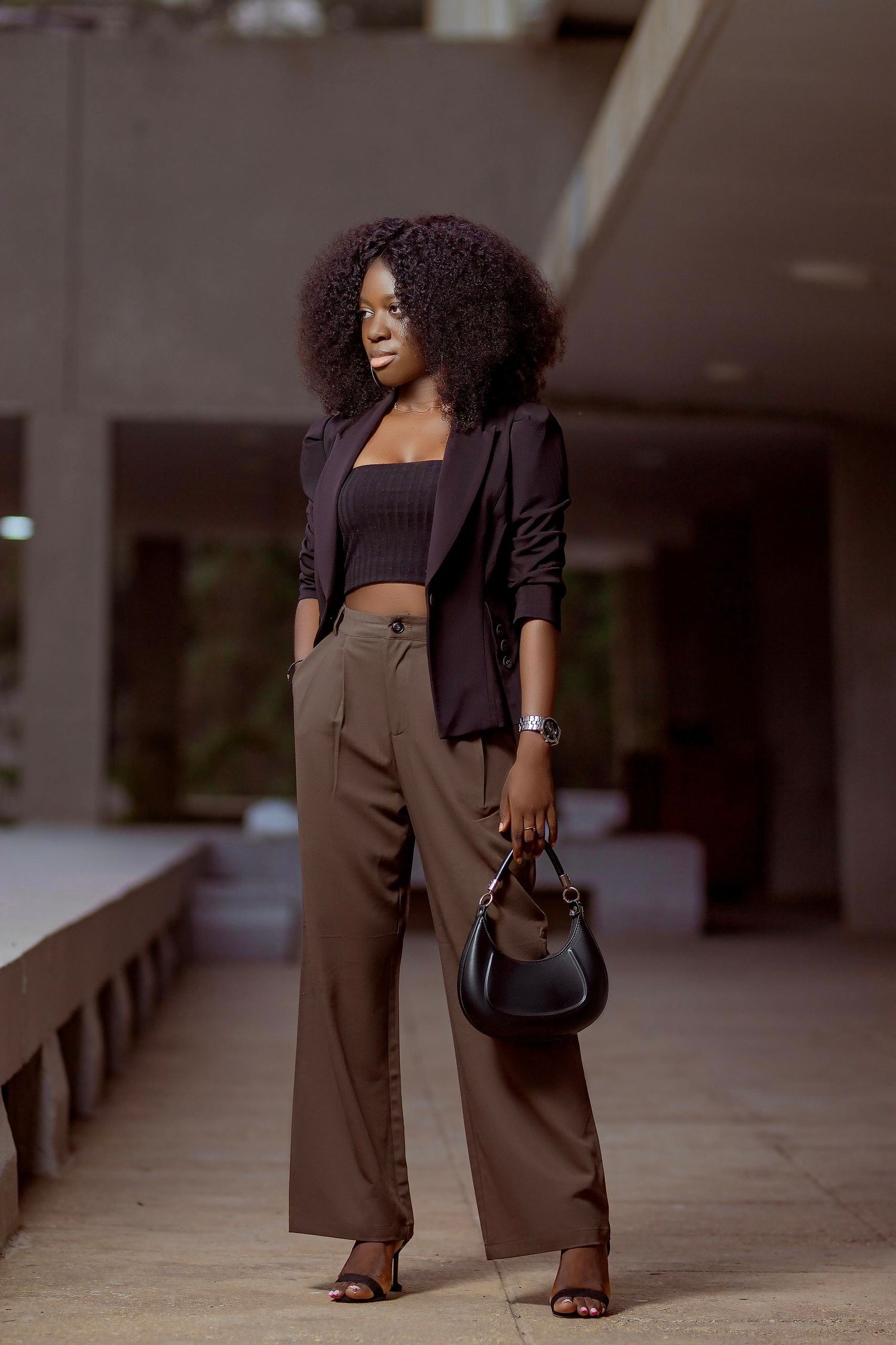 Stylish street fashion look featuring brown trousers, crop top and black blazer with handbag.