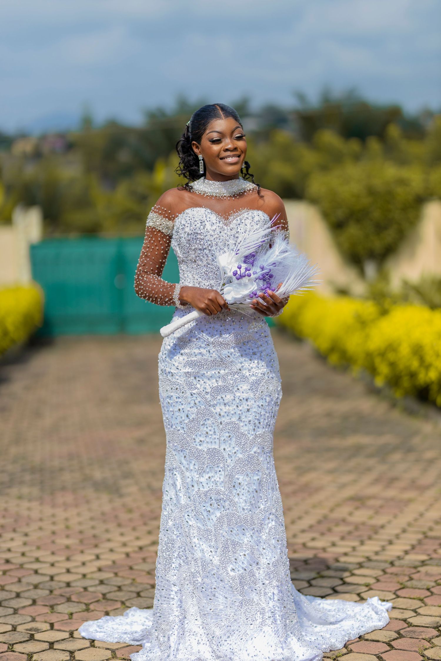 A stunning white lace wedding gown with intricate beading sparkles in an outdoor garden setting.