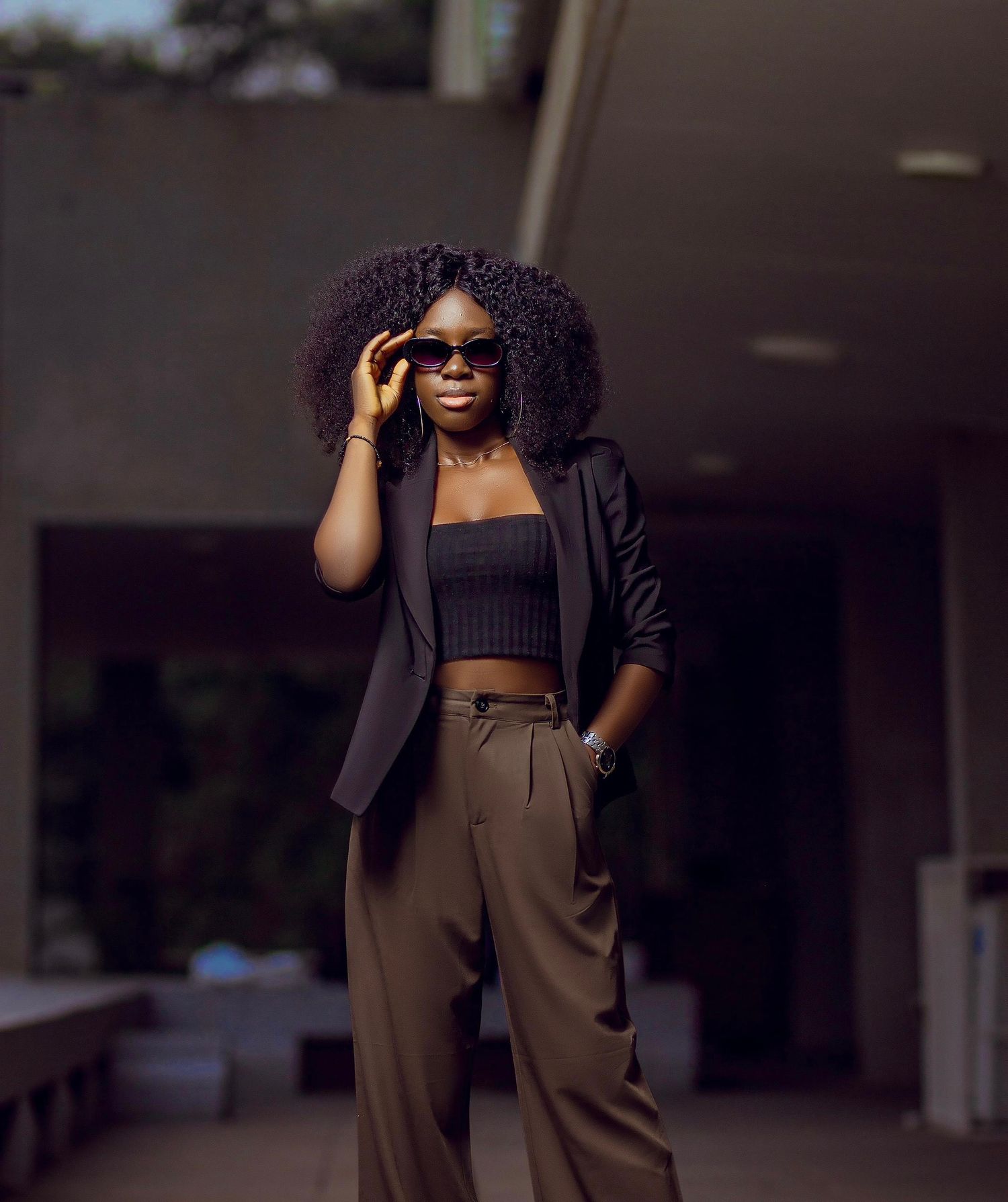 Fashion portrait with blazer, crop top and sunglasses in urban setting.
