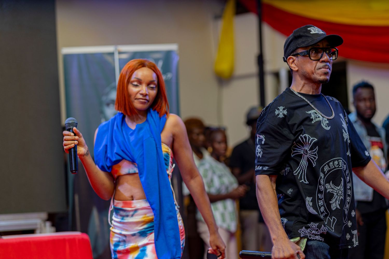 Performers in blue and black outfits entertain on stage during a vibrant cultural event.