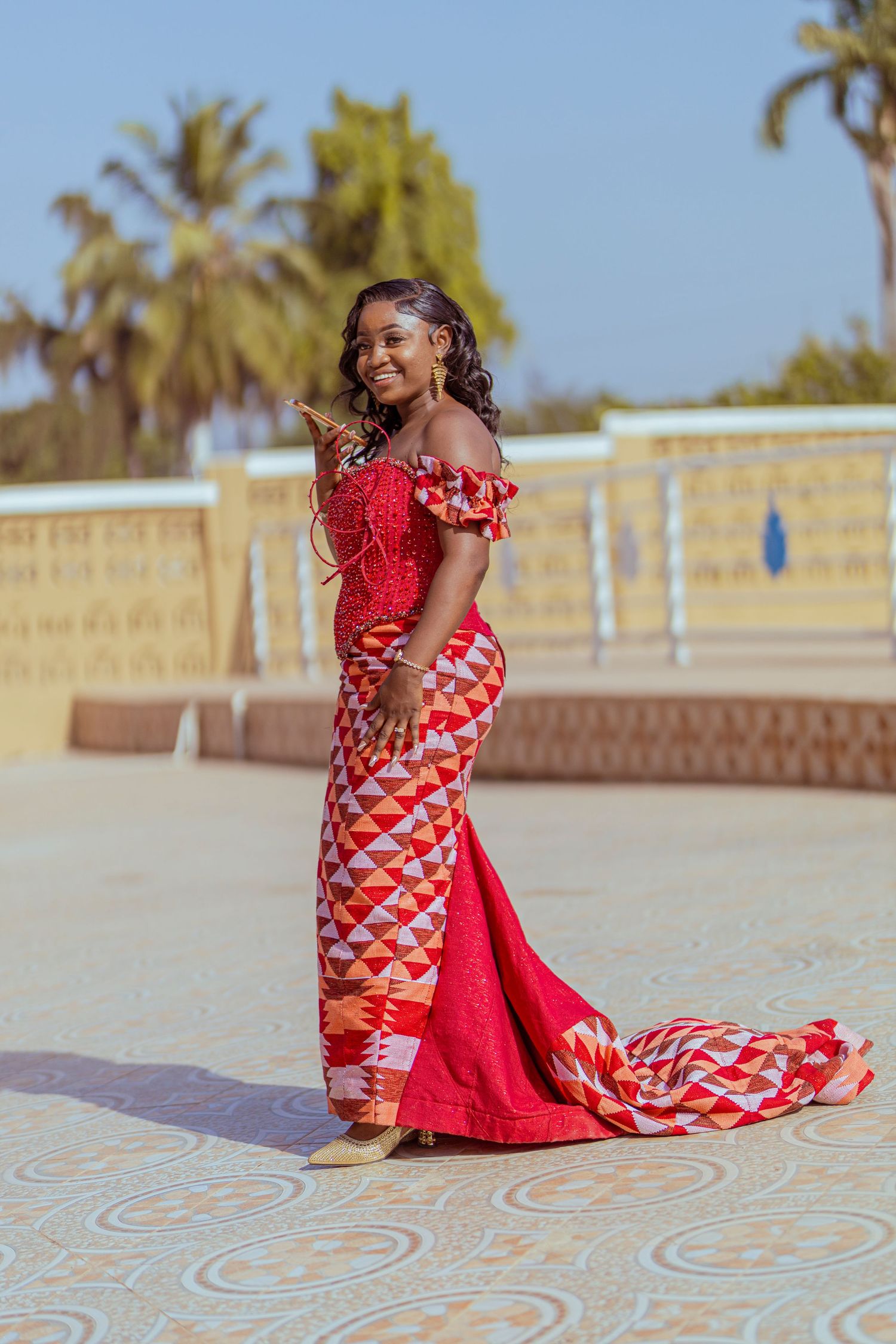 Stunning red and white patterned formal gown with off-shoulder design photographed outdoors.