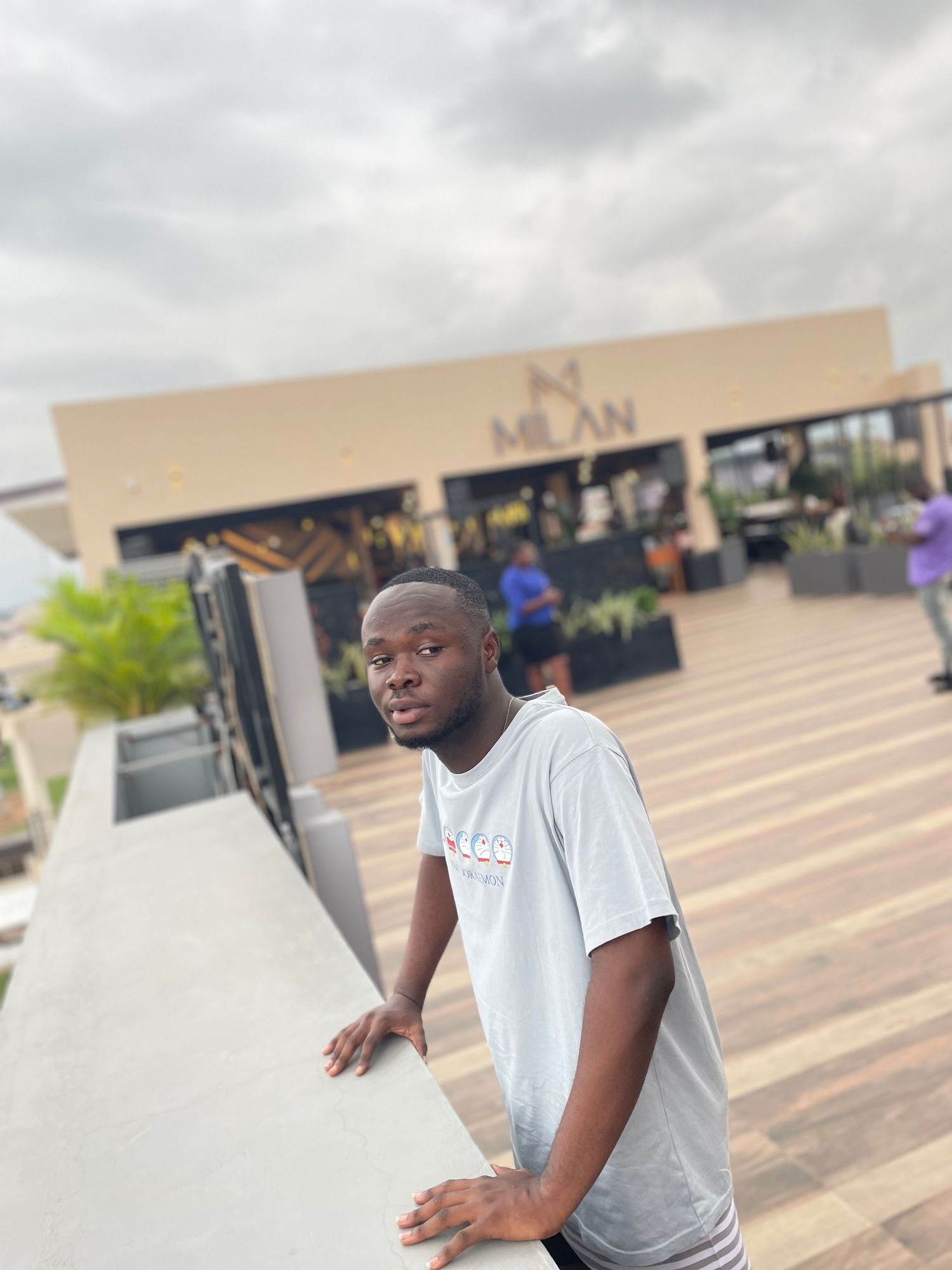 A person in a white t-shirt stands on an outdoor deck.