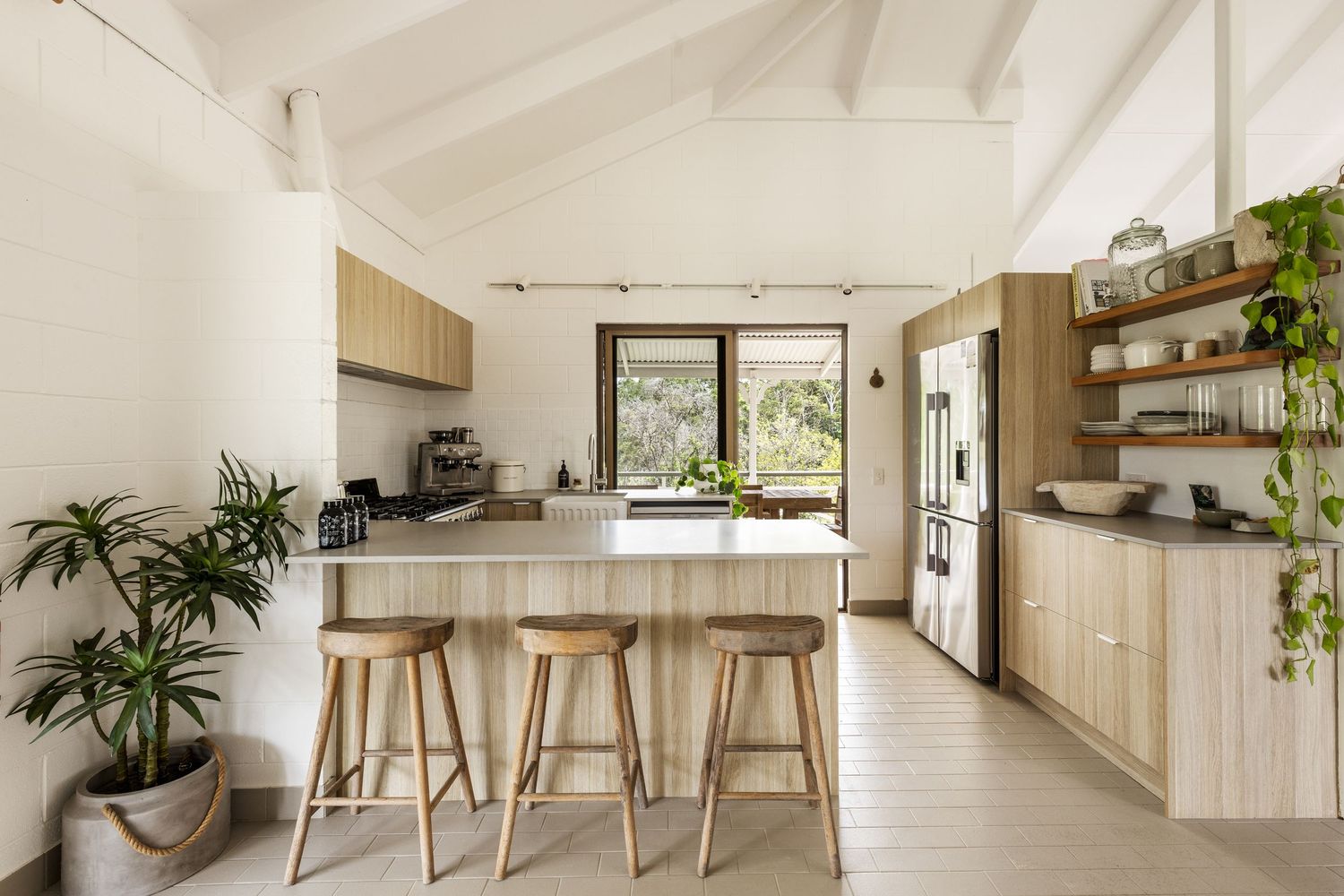 Modern minimalist home interior with white walls, wooden accents and bar stools in an open concept living space.